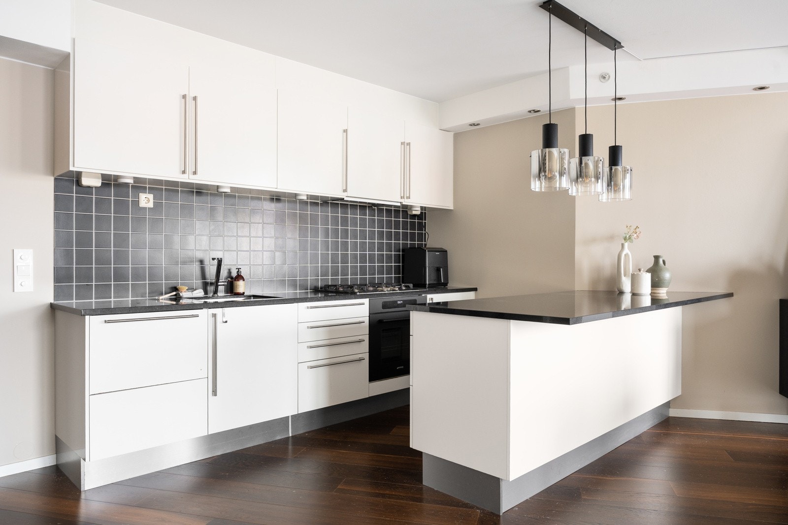 Kjøkkenet har moderne innredning med lyse, slette fronter og benkeplater i stein som gir et stilrent uttrykk. Galleribilde