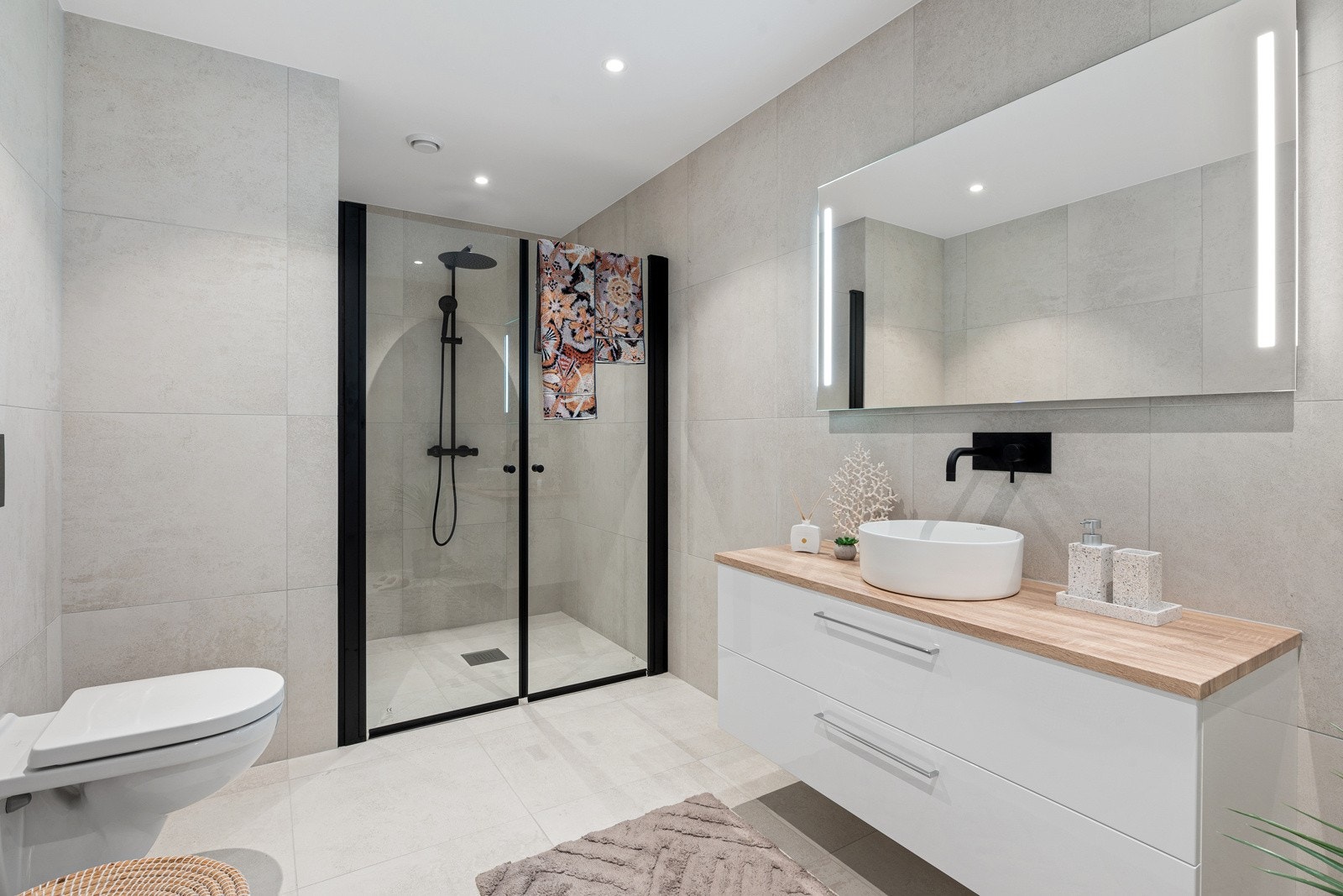 Tiltalende og stilfult bad med stor dusjnisje, veggfestet WC og romslig innredning med servant og speil med ledlys Galleribilde