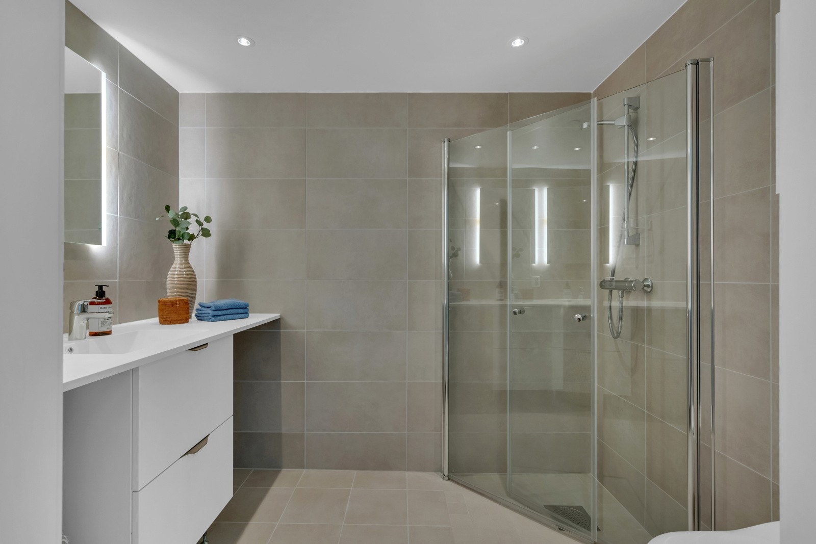 Videre er det vegghengt toalett og dusjhjørne med innfellbare dører. Det er opplegg for vaskemaskin Galleribilde