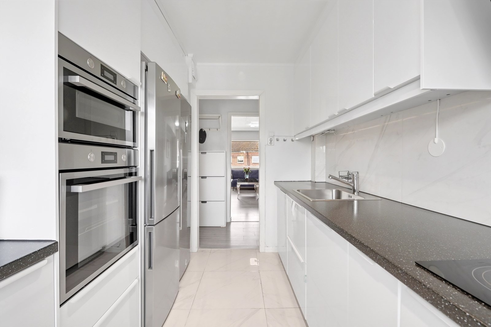 KJØKKEN 2020 | Kjøkkenet har glatte fronter og laminat benkeplate med nedfelt stålkum og ettgrepskran. Fliser mellom benk og overskap, samt stikkontakt over benk. Galleribilde