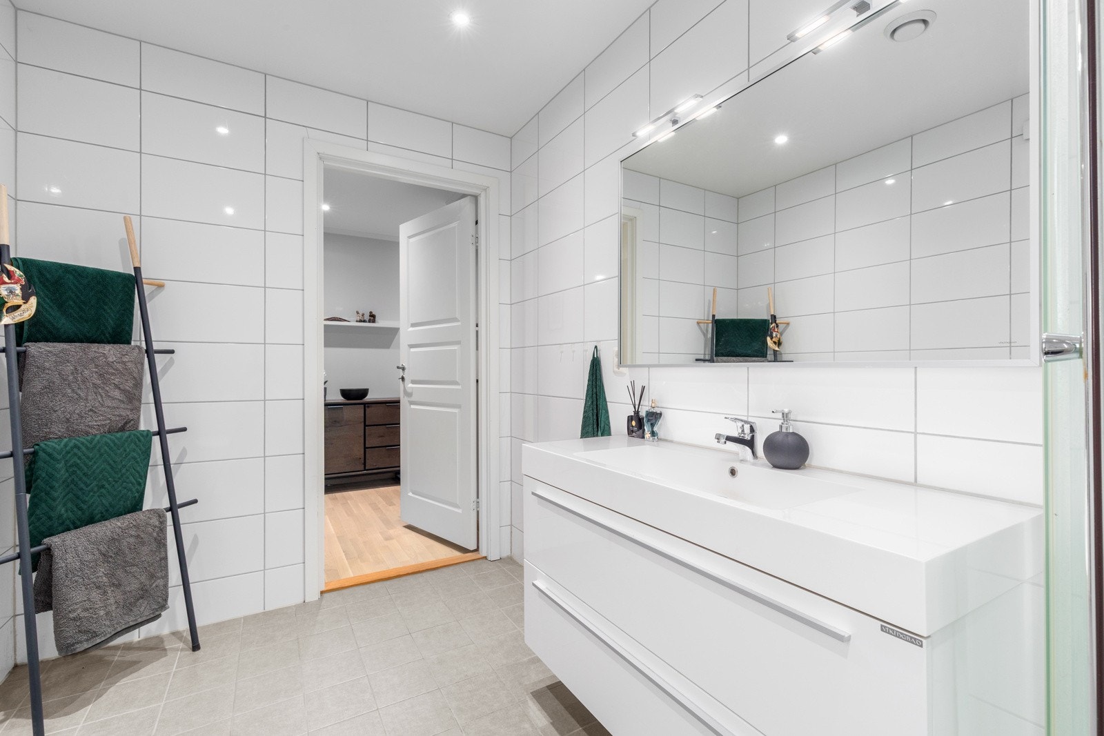 Badet er funksjonelt innredet med servantskap, speil, dusjkabinett og gulvmontert toalett Galleribilde