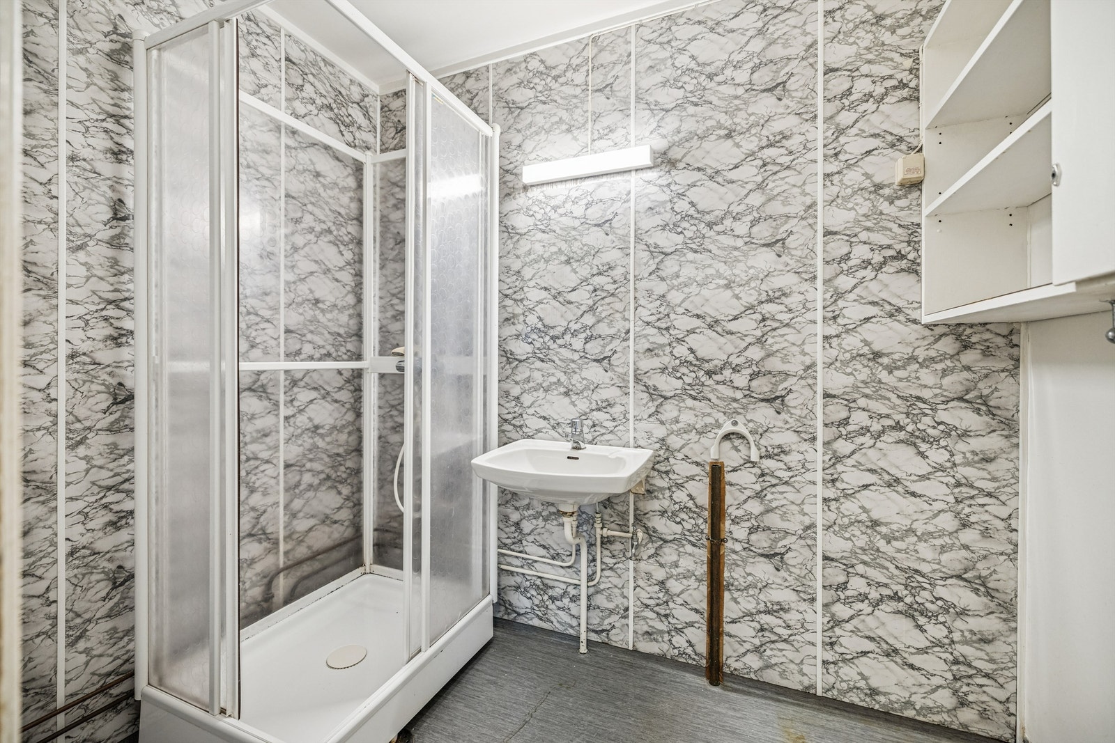 Eldre bad med behov for oppgradering/rehabilitering. Badet er kombinert med vaskerom og er innredet med dusjkabinett og vegghengt servant. Galleribilde