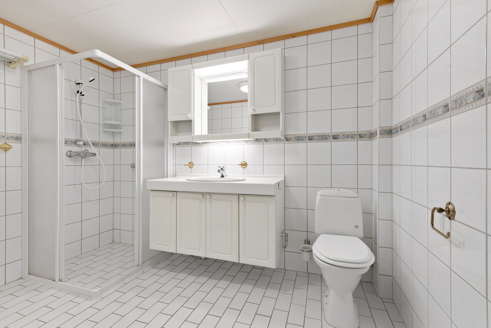 Flislagt bad med innredning, speil m/overlys, gulvstående toalett og dusjhjørne med dusjvegger og vegghengt dusjarmatur Galleribilde