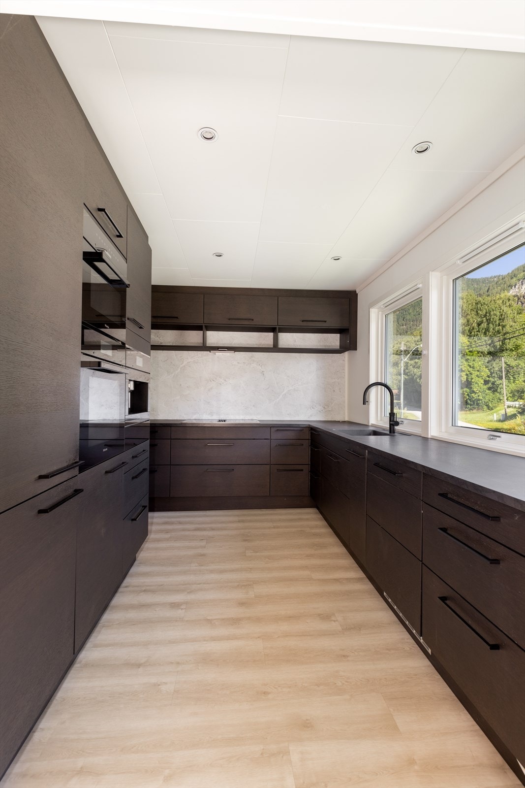 Stekeovn, mikro og kaffemaskin er plassert i praktisk arbeidshøyde i høyskap, og koketoppen har integrert ventilator med avtrekk ut i vegg. Det er montert komfyrvakt over kokesone og vannstoppersystem i kjøkkenbenk. Down-light belysning i tak. Galleribilde