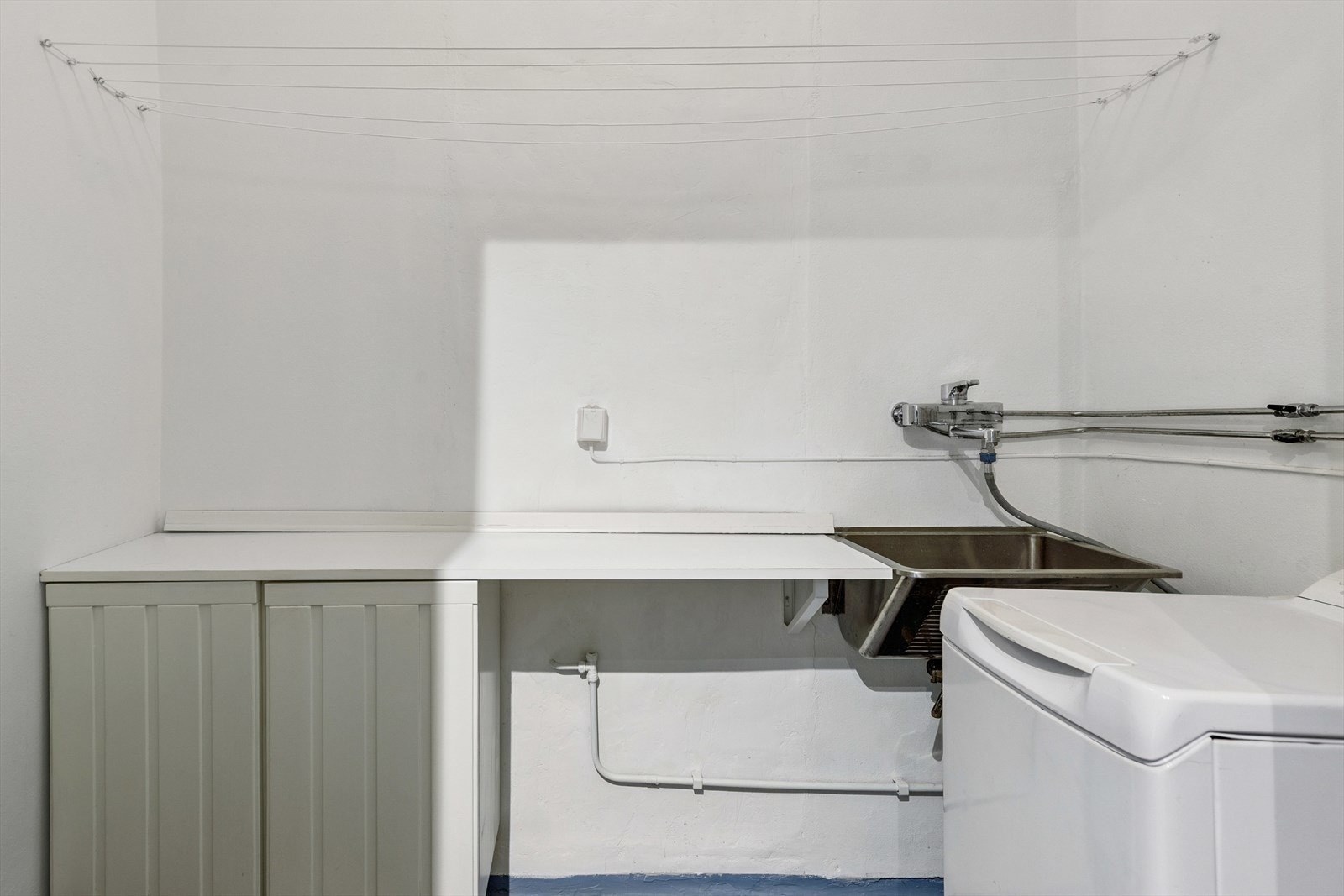 Vaskerom med benk med laminat benkeplate, stålvask samt opplegg for vaskemaskin Galleribilde