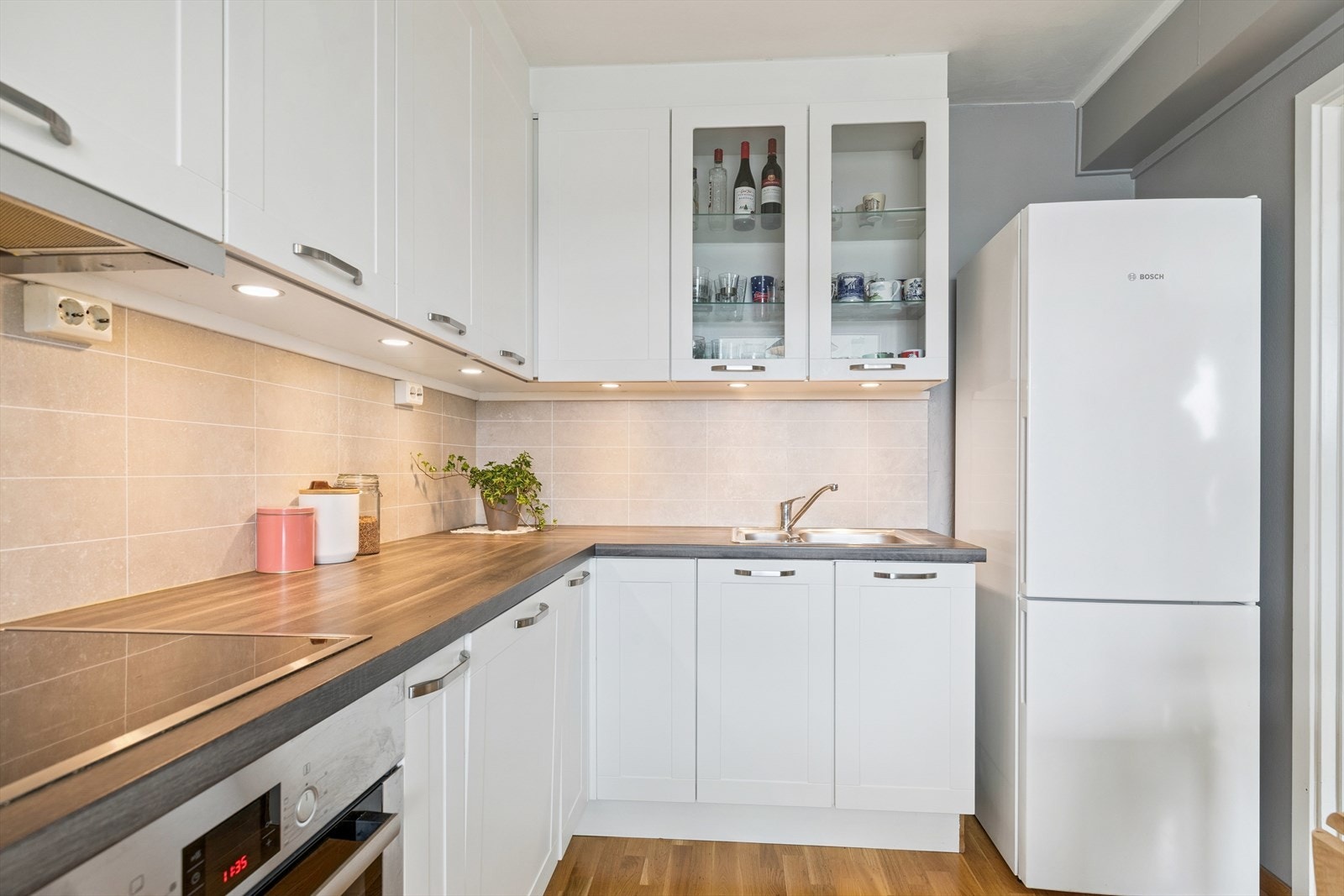 Kjøkkenet har takhøye overskap, kitchen wall mellom benk og overskap, samt integrerte hvitevarer som platetopp, stekeovn og oppvaskmaskin Galleribilde