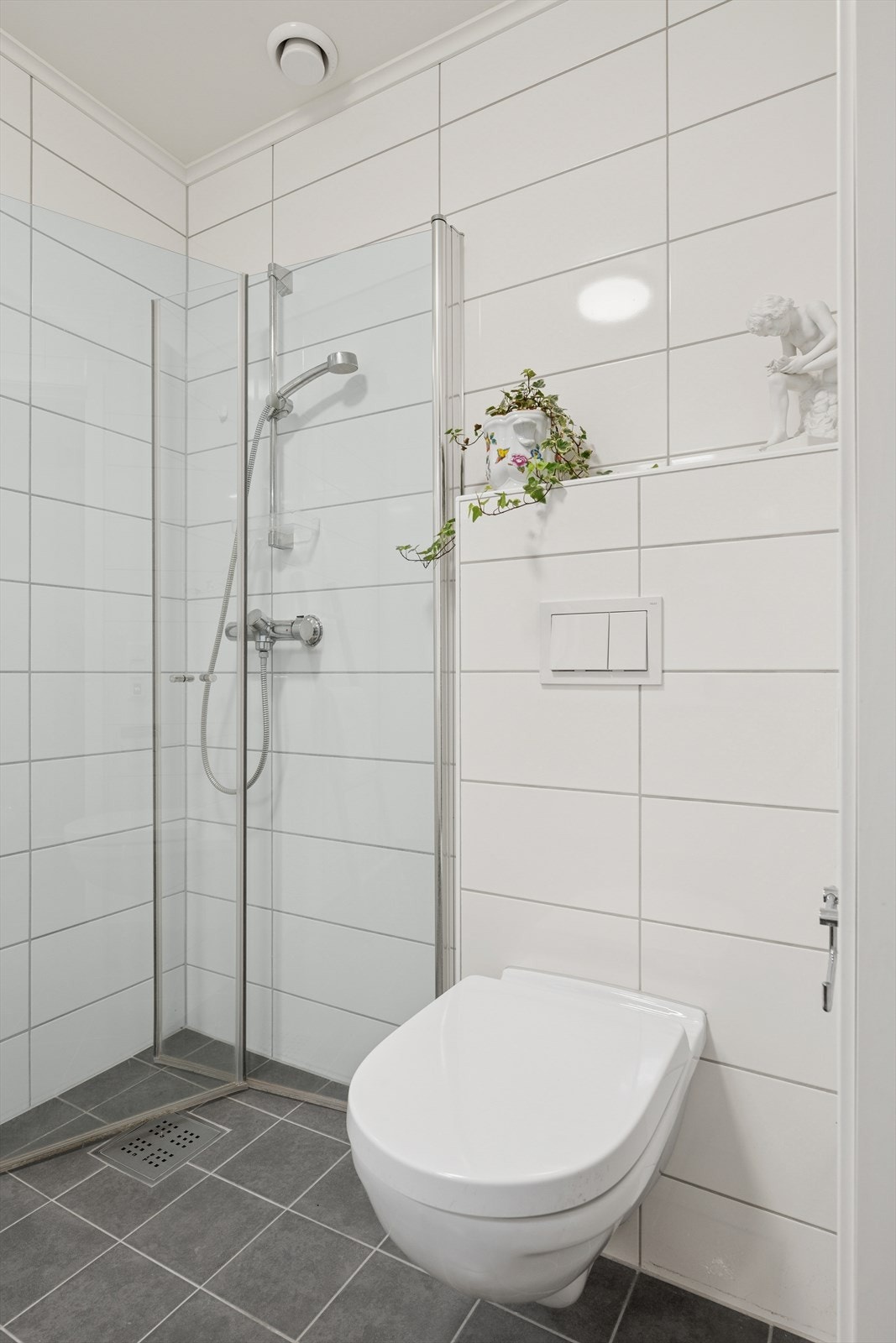 - Rommet er utstyrt med servantinnredning med heldekkende servant topp, speil med tilhørende belysning, vegghengt toalett, skap og et dusjhjørne med dusjopplegg på vegg og glassdører - Galleribilde