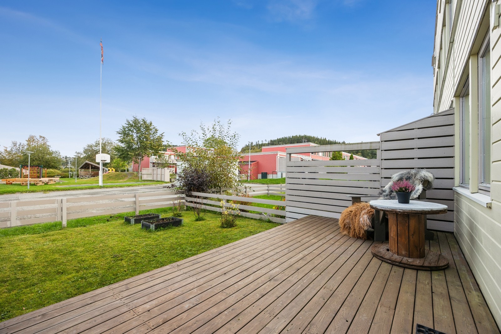 Terrassen vender mot en inngjerdet hageparsell med rom for beplantning og like utenfor hagen er det en lekeplass og friområder. Galleribilde