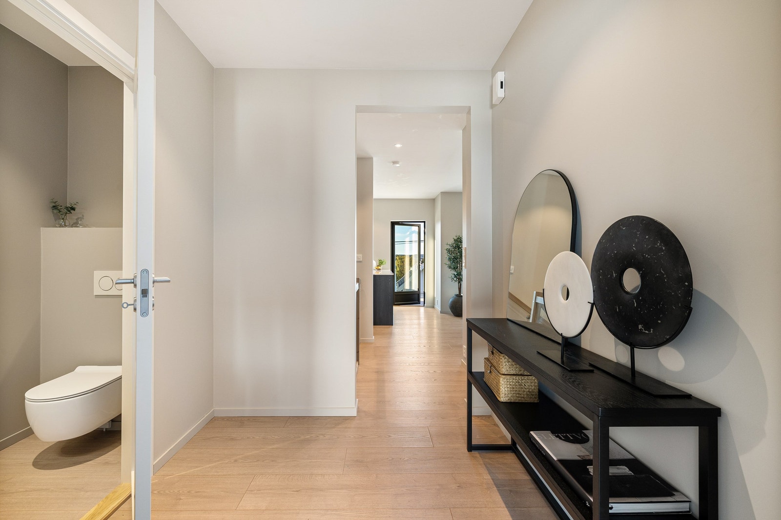 Lys og romslig entré med lang siktlinje mot uteplass og varme eikegulv som inviterer videre inn i boligen. Galleribilde