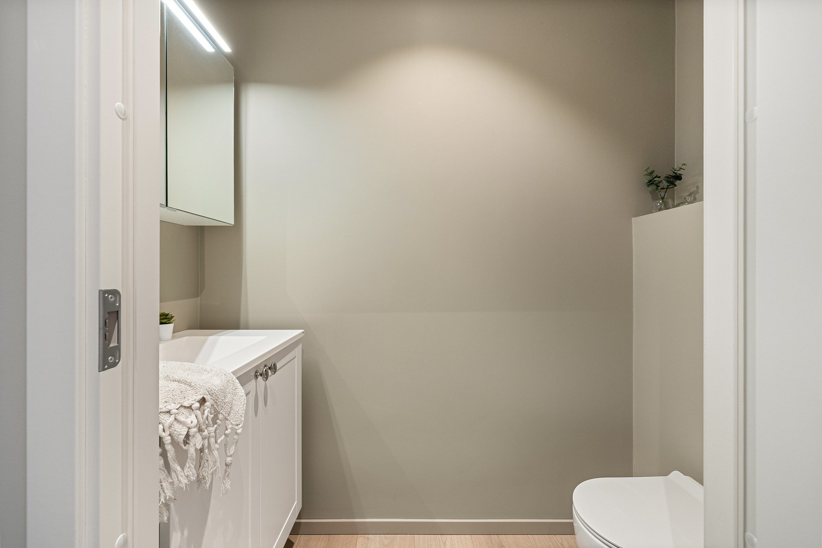 Toalettet i tilknytning til gangen har lyse, varme overflater. Speilskapet har effektiv belysning, og plass til litt oppbevaring. Galleribilde