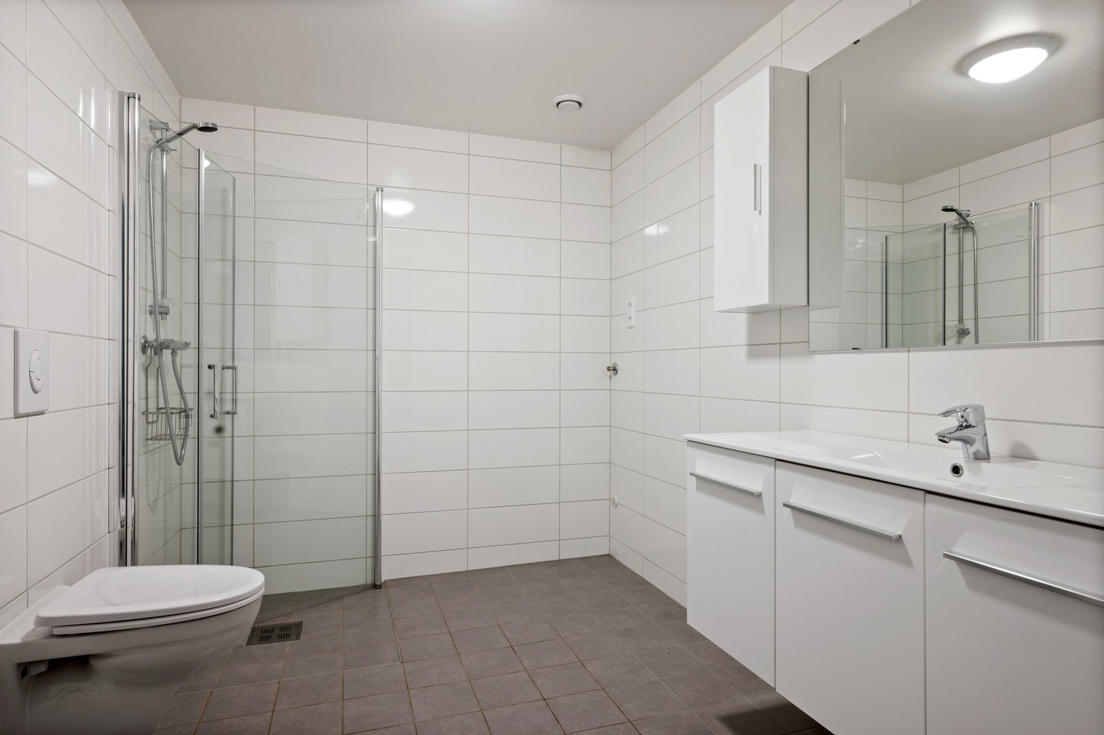 Flislagt baderom, godt utstyrt med innredning med servant, wc og dusjnisje Galleribilde