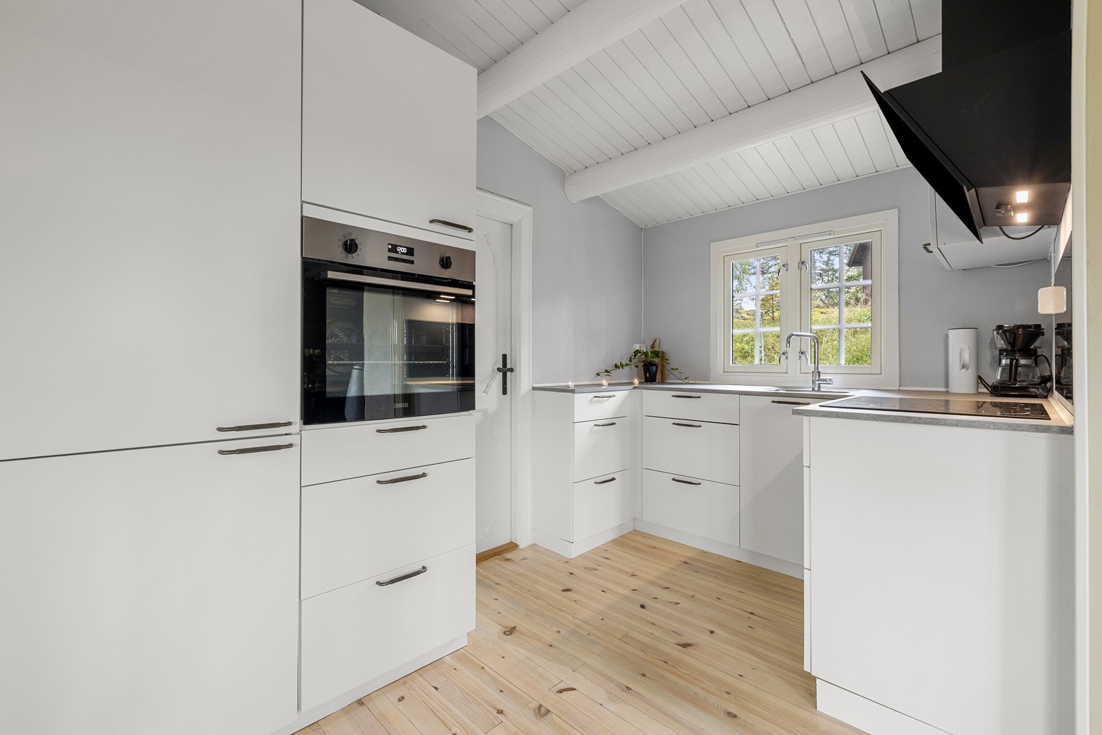 Tidløs og klassisk kjøkkeninnredning med hvite glatte fronter og laminat benkeplate. Galleribilde