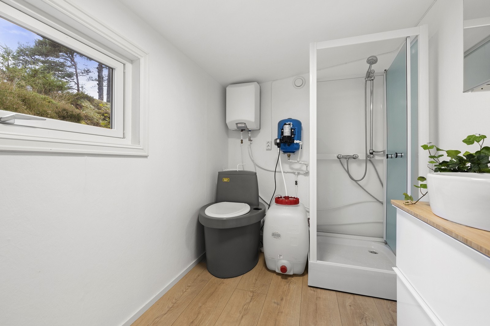 Pent innredet bad med biologisk toalett, dusjkabinett, varmtvannsbeholder, vanntank og moderne innredning. Galleribilde