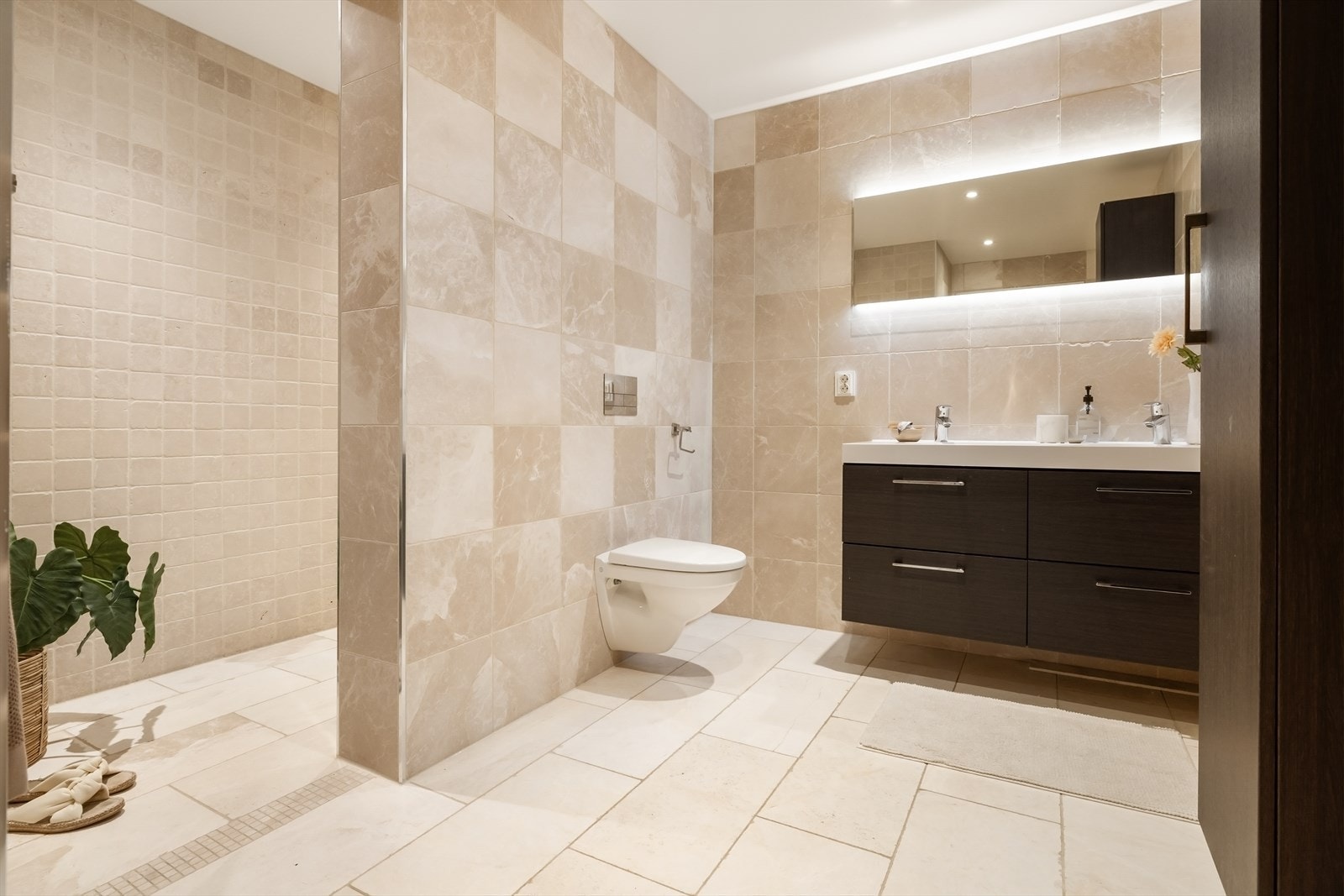 Badet har varme i gulv og inneholder vegghengt servantinnredning med skuffer og baderomsmøblel, speil med lys, vegghengt toalett, dusjnisje, og downlights i himling. Galleribilde