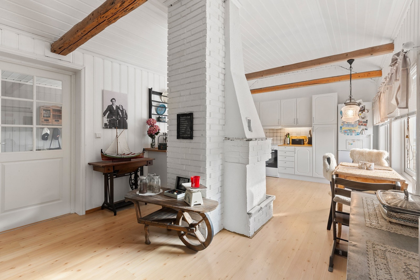 Kjøkkenet er innredet i en hjemmekoselig og sjarmerende stil med synlige bjelker og lune materialer. Galleribilde