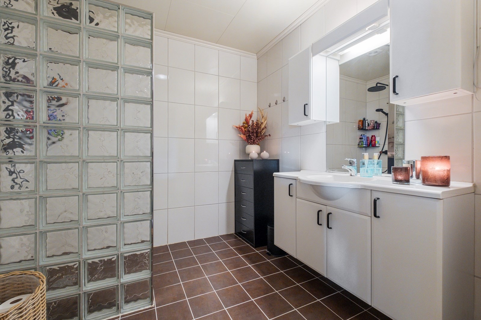 Bad i 1. etasje. Veggene har fliser. Taket har himlingsplater. Gulvet er flislagt. Rommet har elektriske varmekabler. Rommet har innredning med nedfelt servant, toalett og dusjvegger/hjørne med glassbyggerstein Galleribilde