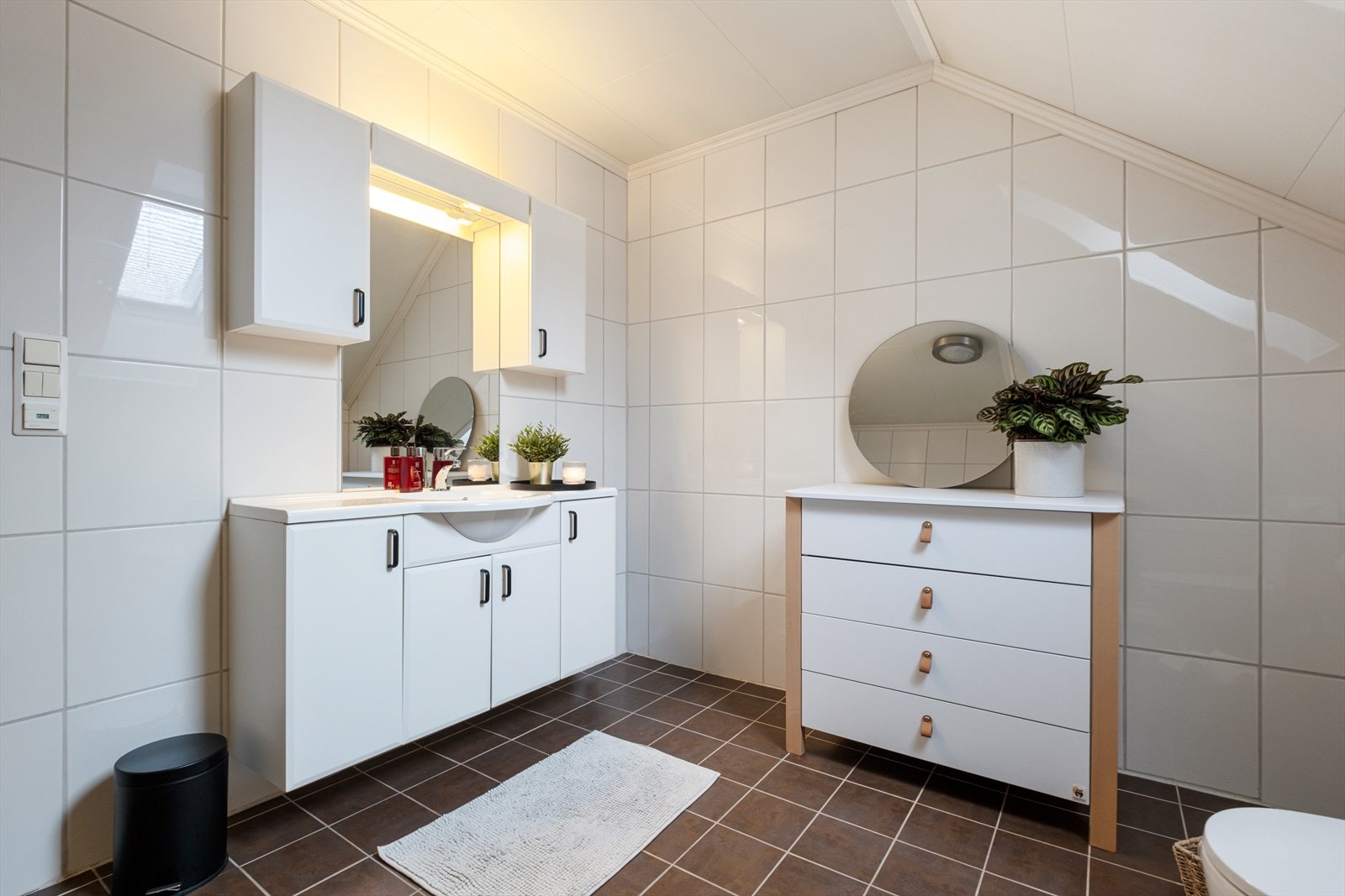 Bad på loftet. Veggene har fliser. Taket har himlingsplater. På gulv er det fliser og det er varmekabler i gulvet. Rommet har innredning med nedfelt servant, toalett og badekar. Galleribilde