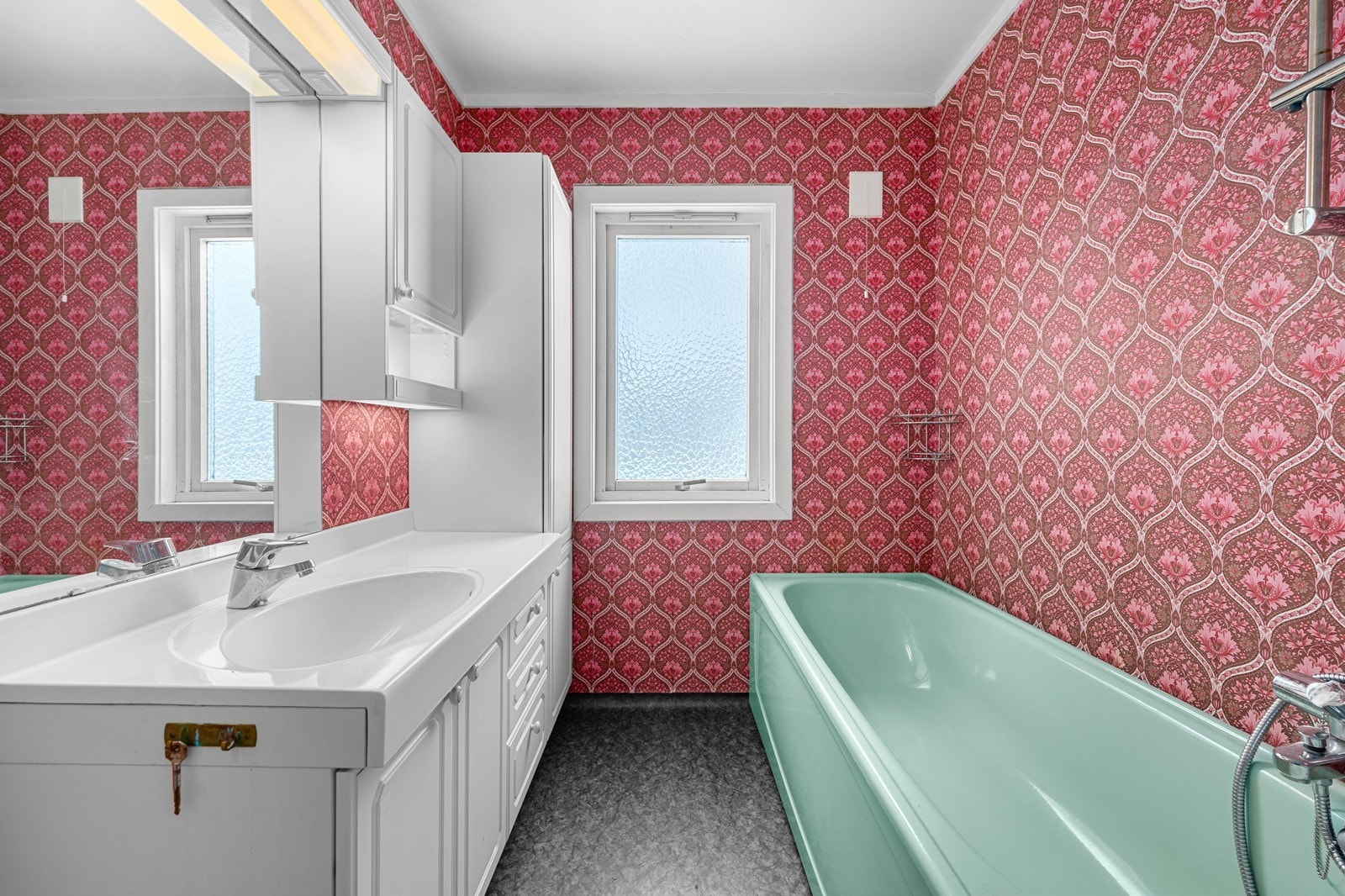 Baderommet er utstyrt med toalett og badekar i mint, og servant på skapseksjon med overspeil og belysning. Galleribilde