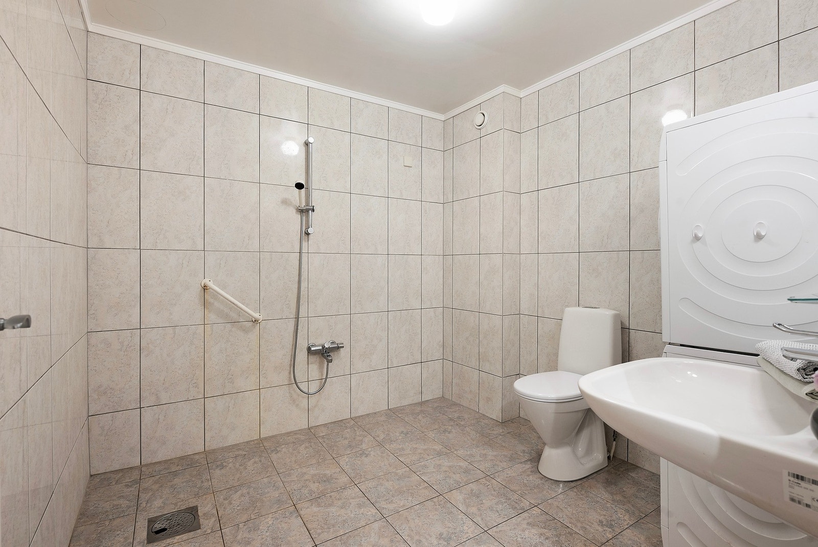 Badet er flislagt på både gulv og vegger. Taket er malt. Gulvet har elektriske varmekabler, plastsluk og vinylbelegg fra byggeår som tettesjikt Galleribilde