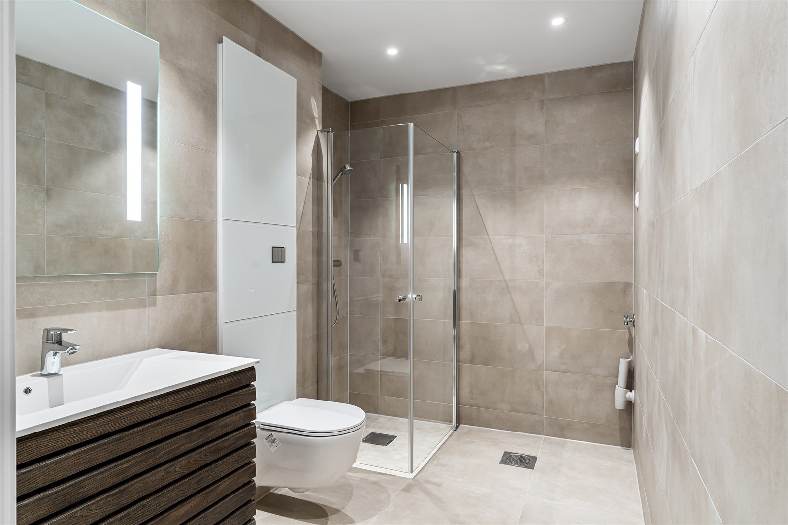 Elegant kombinert baderom og vaskerom med store fliser på gulv og vegger Galleribilde