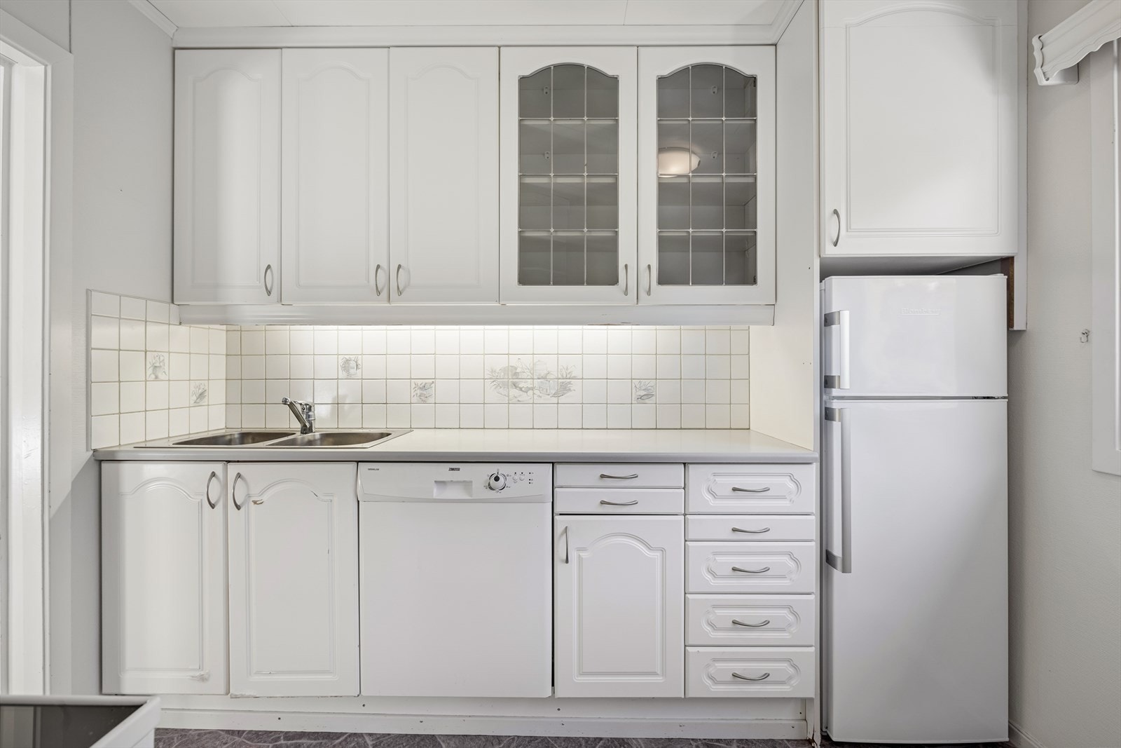 Profilert kjøkkeninnredning med fliser mellom over- og underskap. Galleribilde