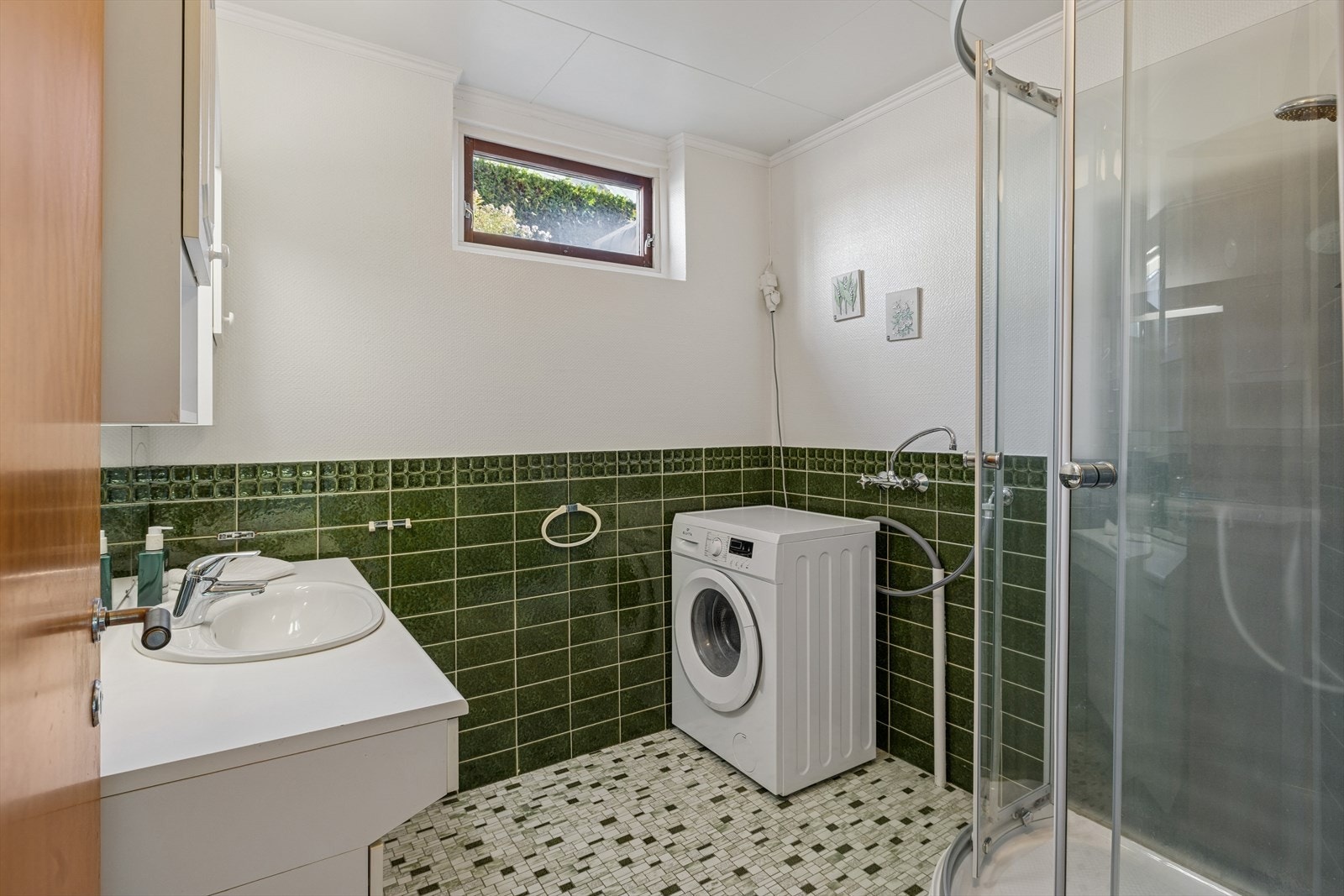 Baderommet er innredet med dusjkabinett og opplegg til vaskemaskin. Galleribilde