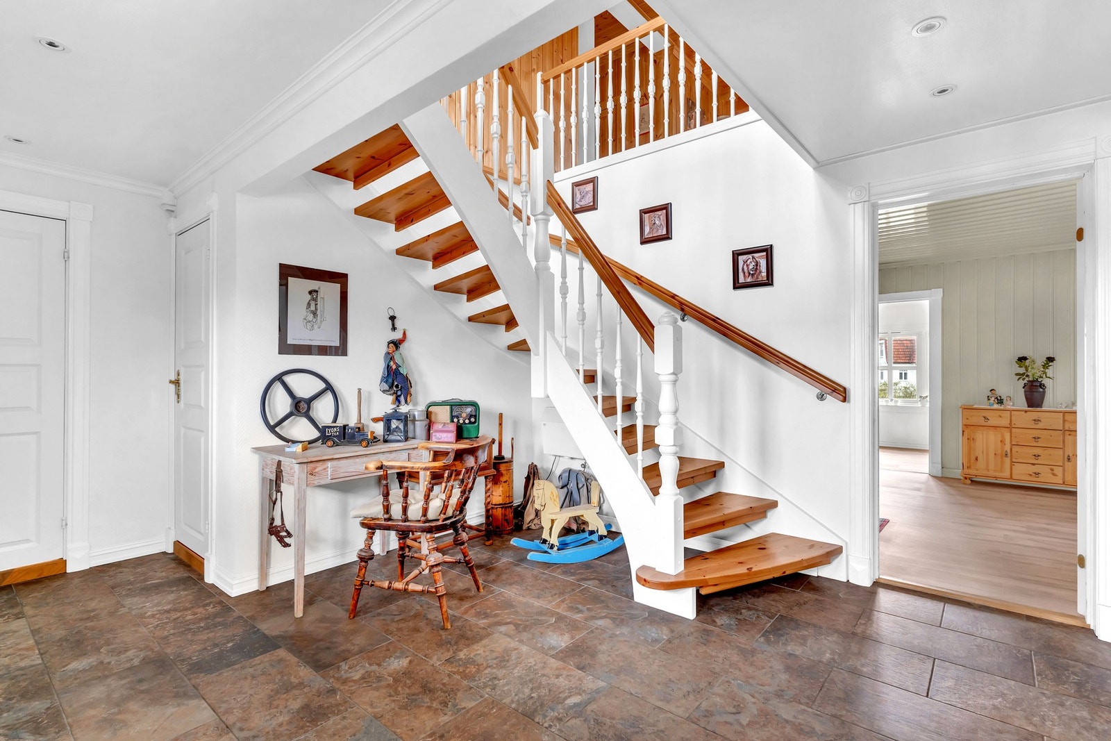 Her er det inngang til en stor og lys entré med hvite vegger, mørke fliser på gulv, downlights i himling og gulvvarme. Galleribilde