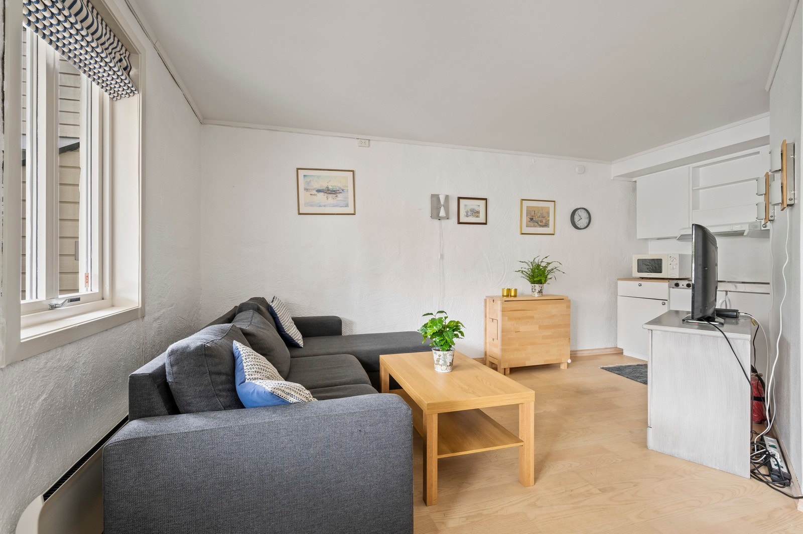 Leiligheten har stue med plass til sofa og ligger i en åpen løsning mot kjøkkenet Galleribilde