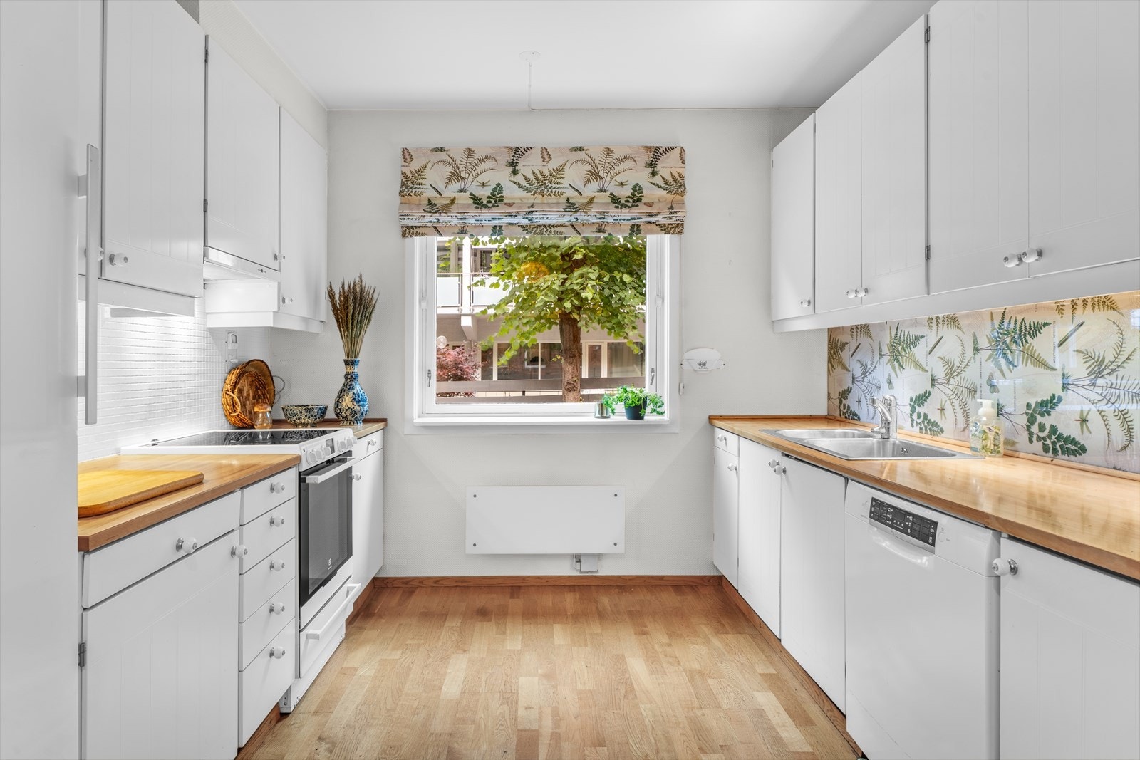 Separat kjøkken med heltre benkeplate, innredning med glatte fronter og vindu på endevegg Galleribilde