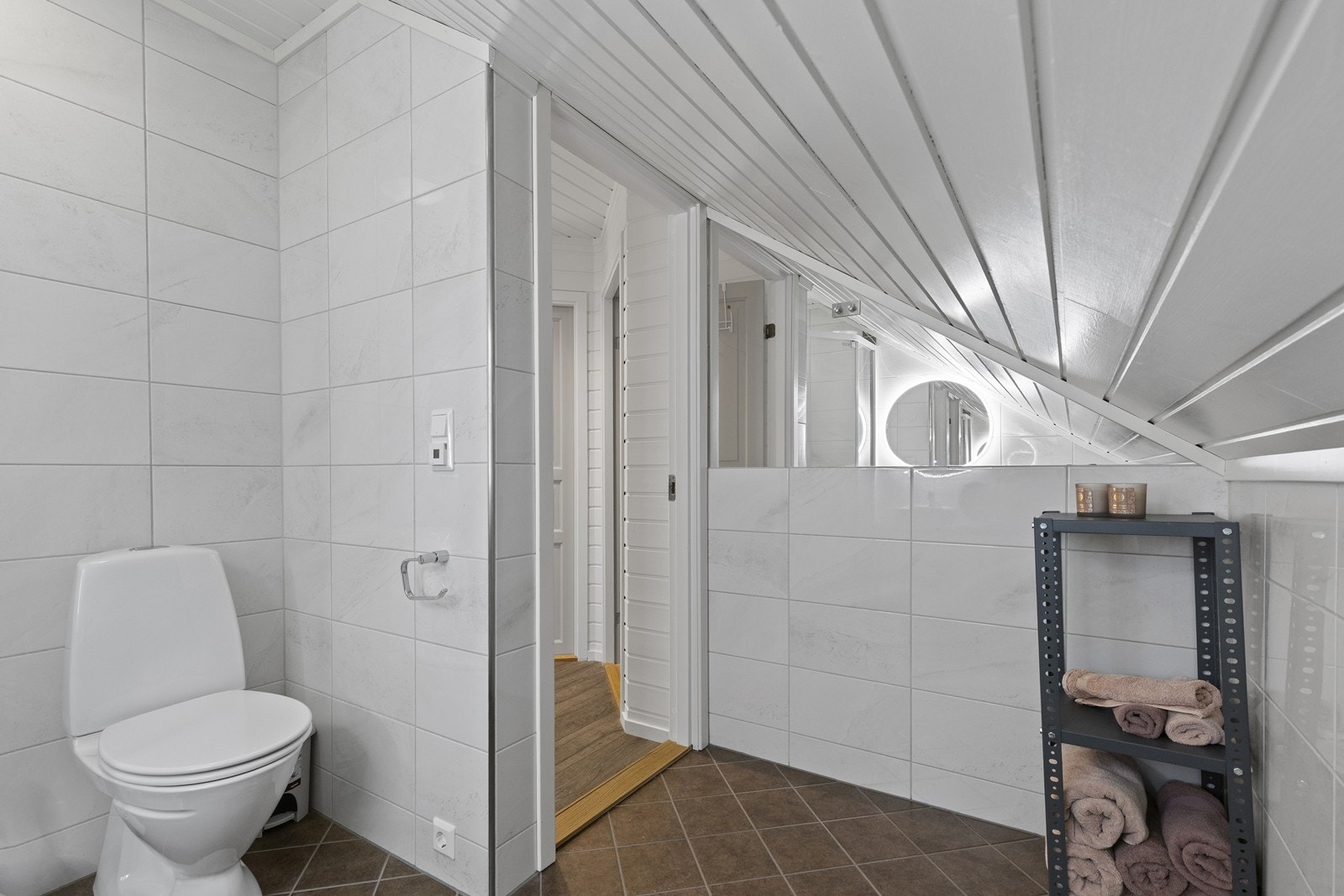 Loftsbaderommet har fliser, gulvvarme og skråtak, samt dusjhjørne, servant og toalett. Galleribilde