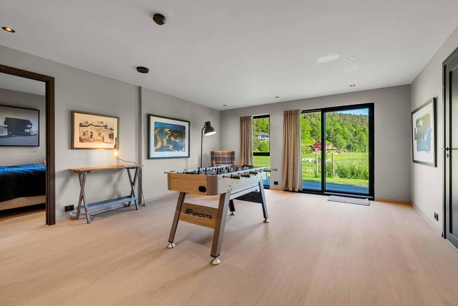 Lyst og romslig oppholdsrom med store vinduer og flott utsikt til grønne omgivelser. Perfekt for spill og avslapning..jpg Galleribilde