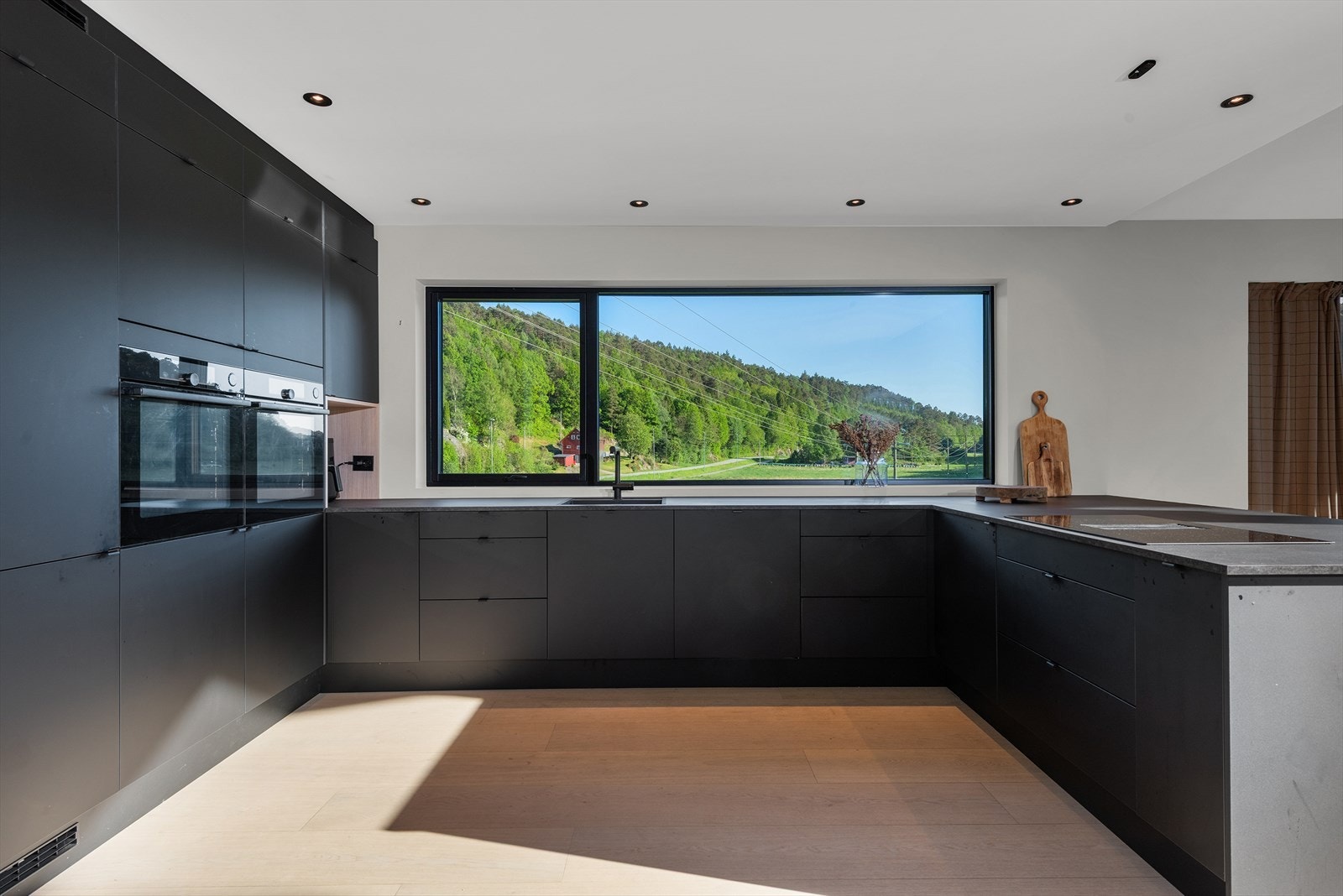Moderne kjøkken med store vinduer som gir fantastisk utsikt mot frodig natur. Perfekt for matlaging i lyse omgivelser..jpg Galleribilde