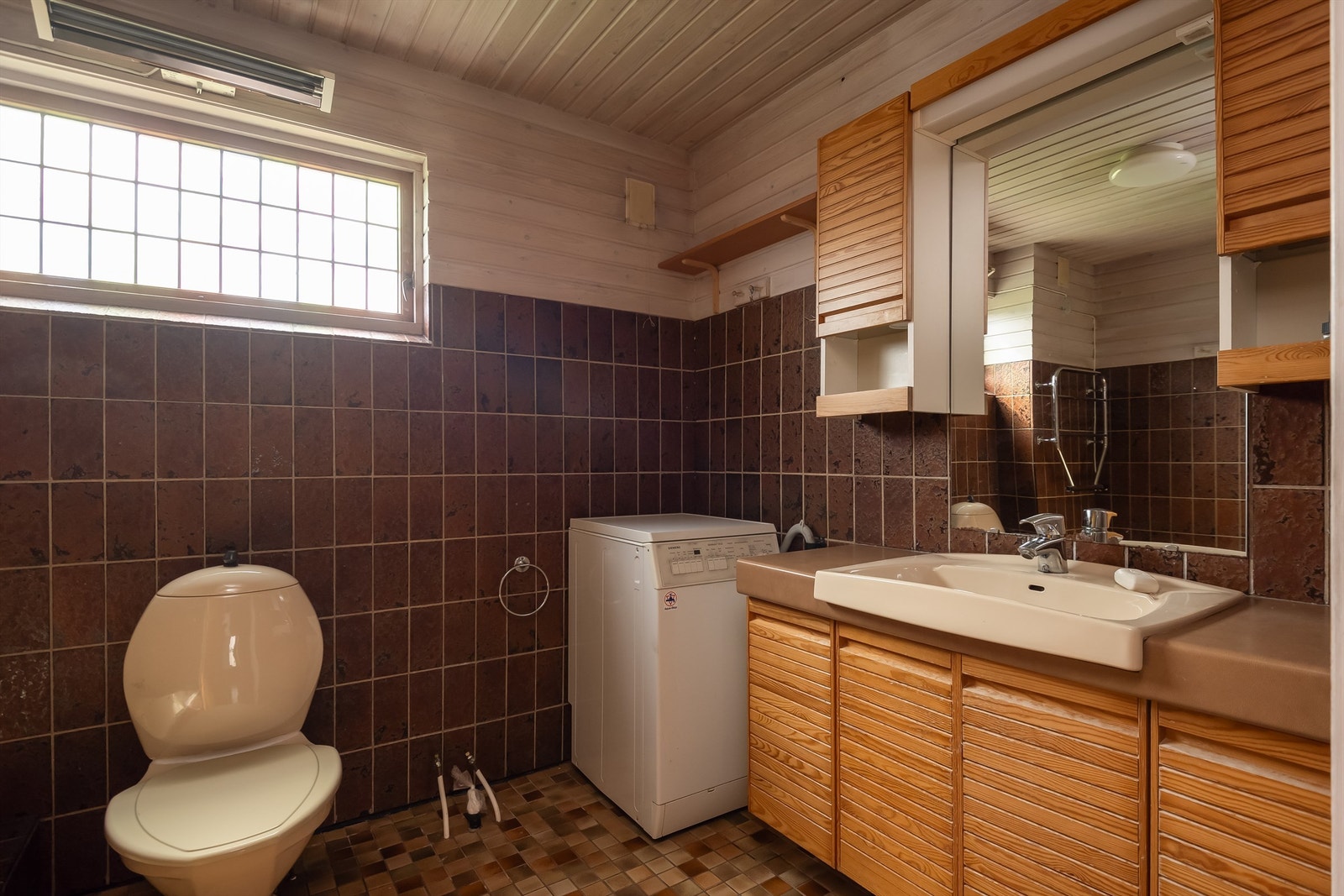 Pent delvis flislagt bad med opplegg for vaskemaskin. Galleribilde