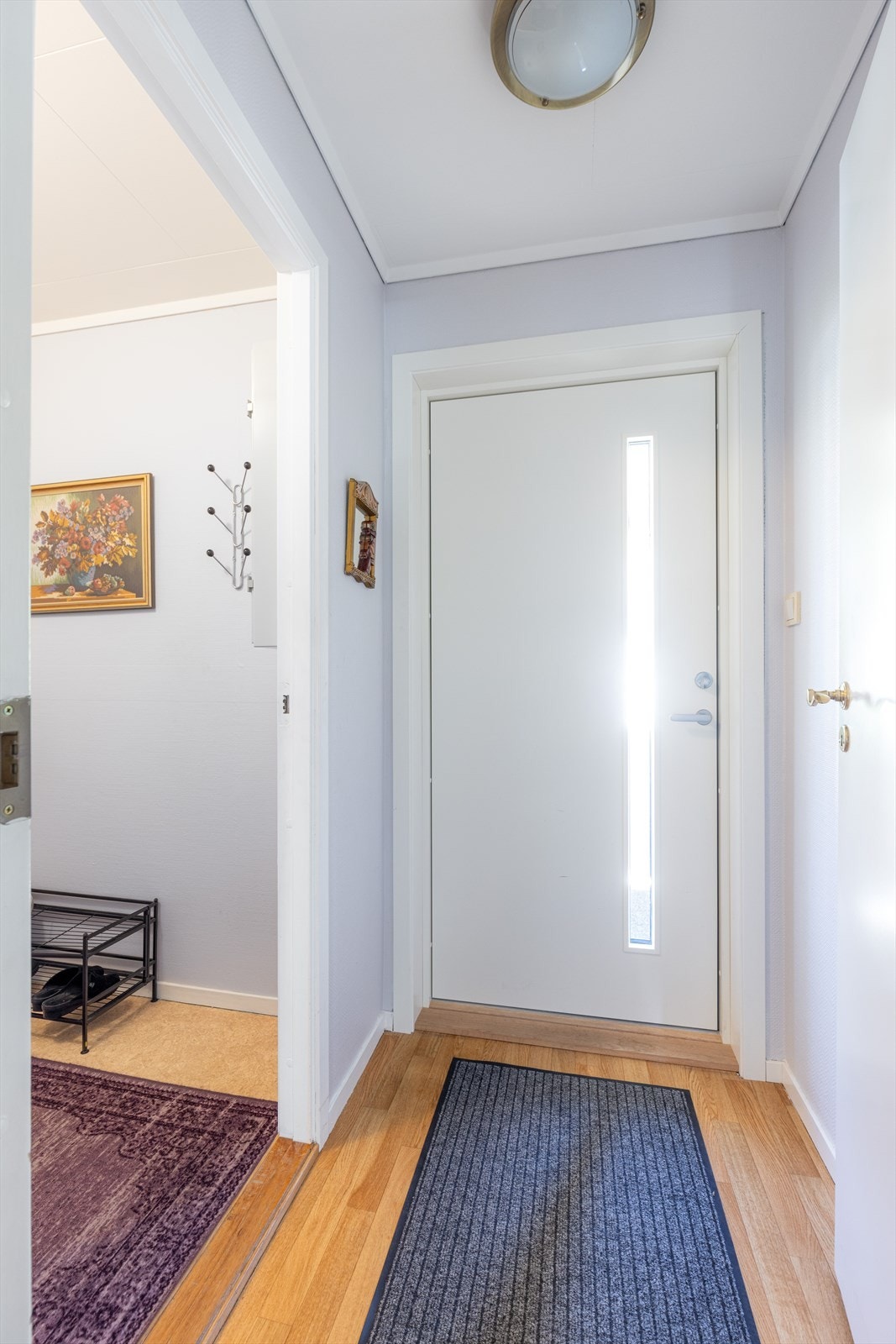 Liten entré med lyse overflater og ny, moderne ytterdør fra 2024. Galleribilde