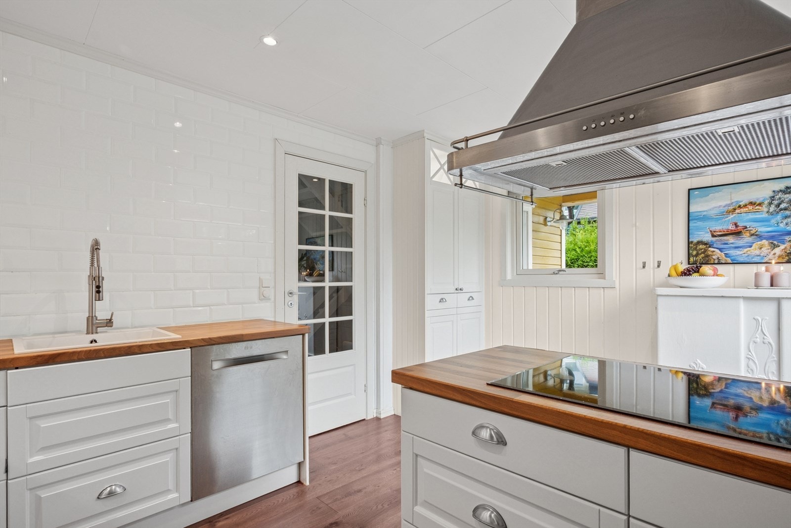 Hvite, profilerte fronter kombinert med en varm trefarget laminat benkeplate gir kjøkkenet en fin kontrast og et innbydende uttrykk. Galleribilde