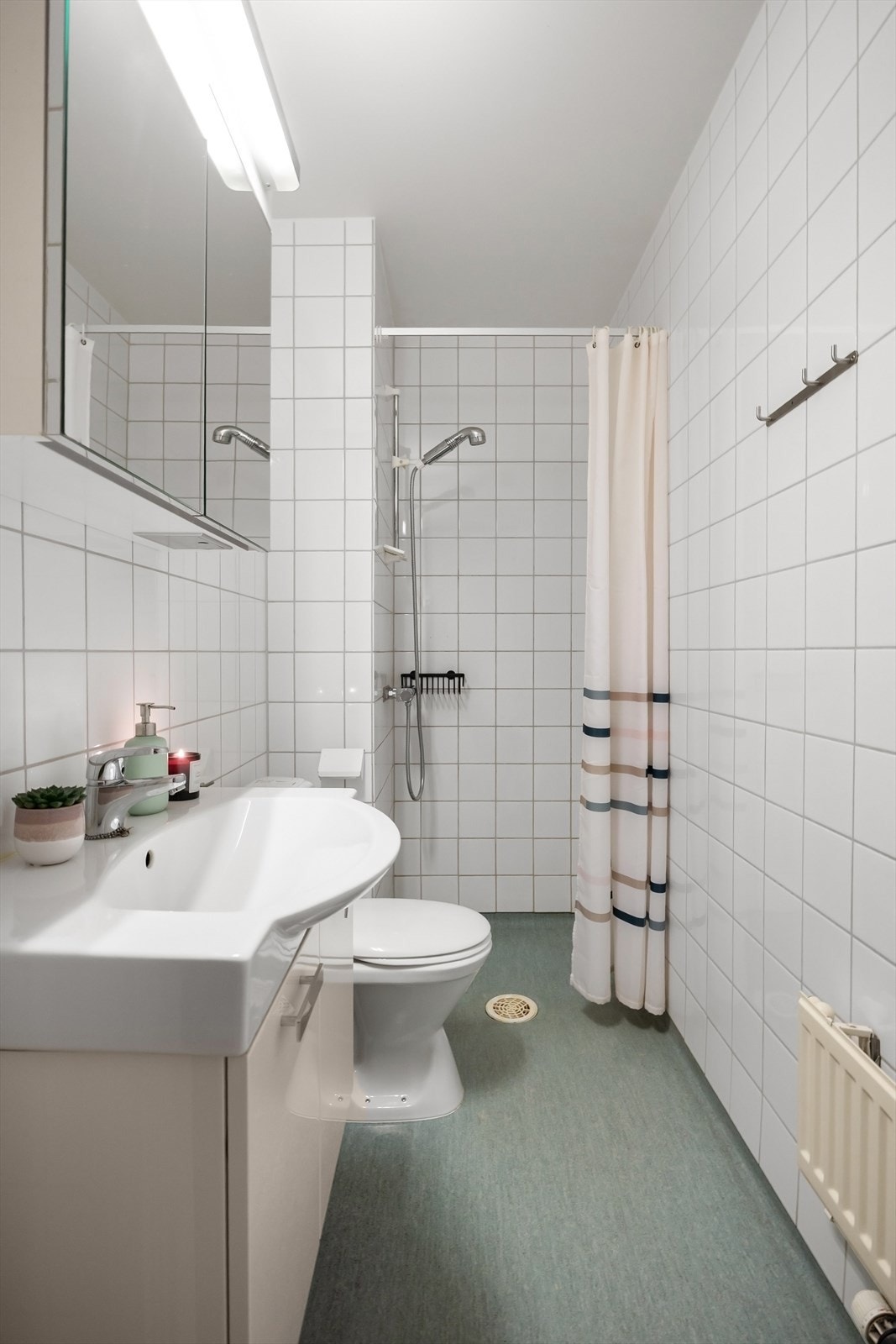 Bad med overflater som består av belegg på gulv, fliser på vegger og malt overflate i himling. Galleribilde