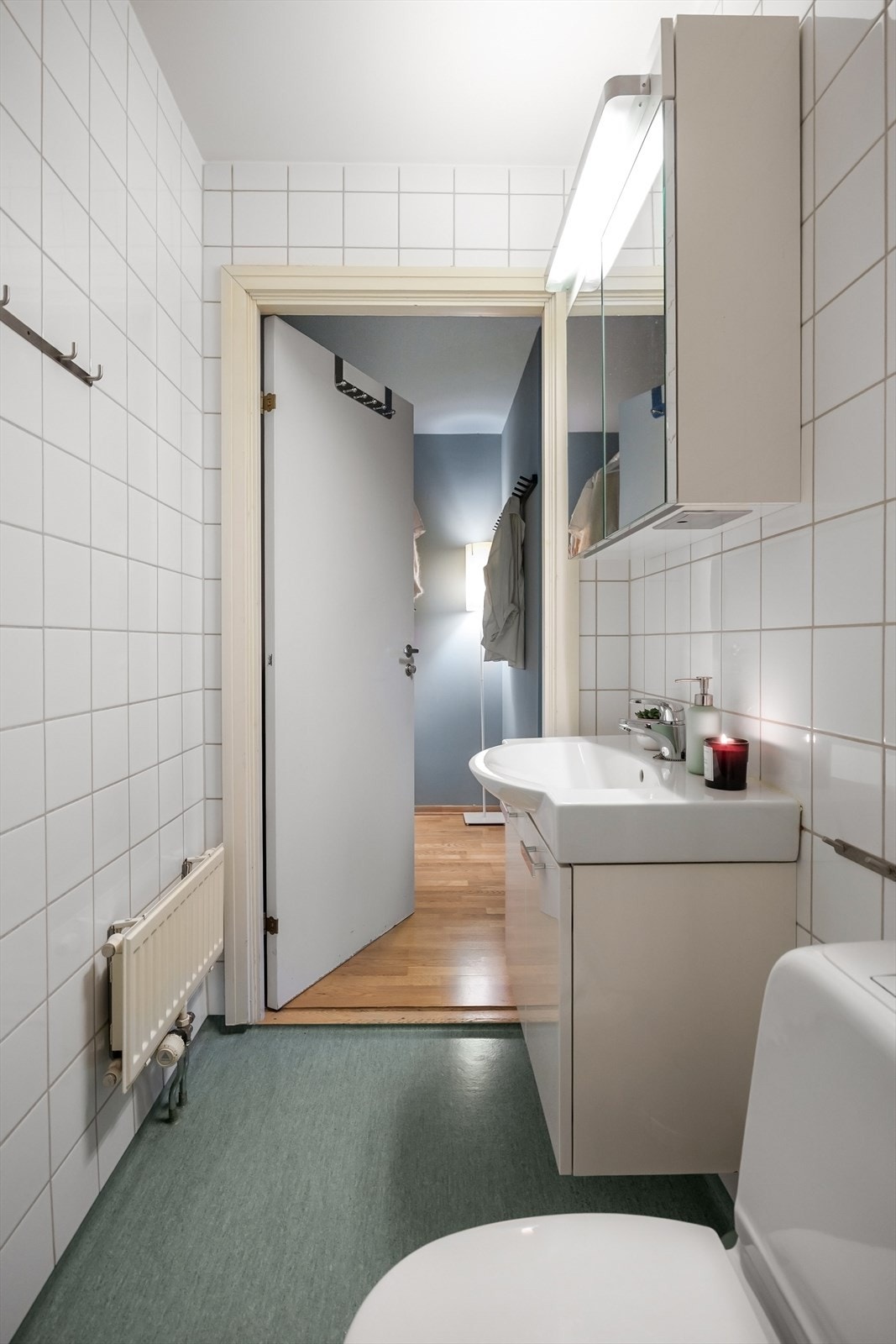 Badet er utstyrt med dusjnisje med forheng, gulvstående toalett og baderomsinnredning med skap, overlimt servant med ettgreps armatur fra Oras og speilskap med lys. Galleribilde