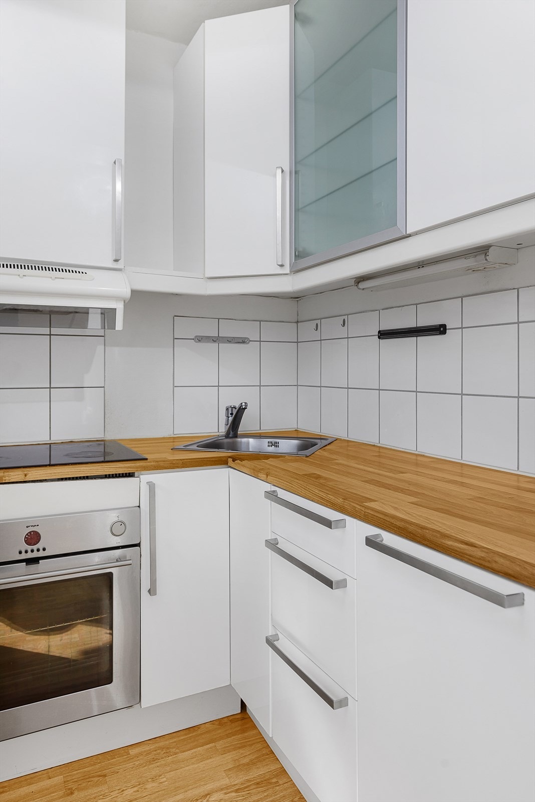 Det er flislagt mellom benkeplaten og overskapene Galleribilde