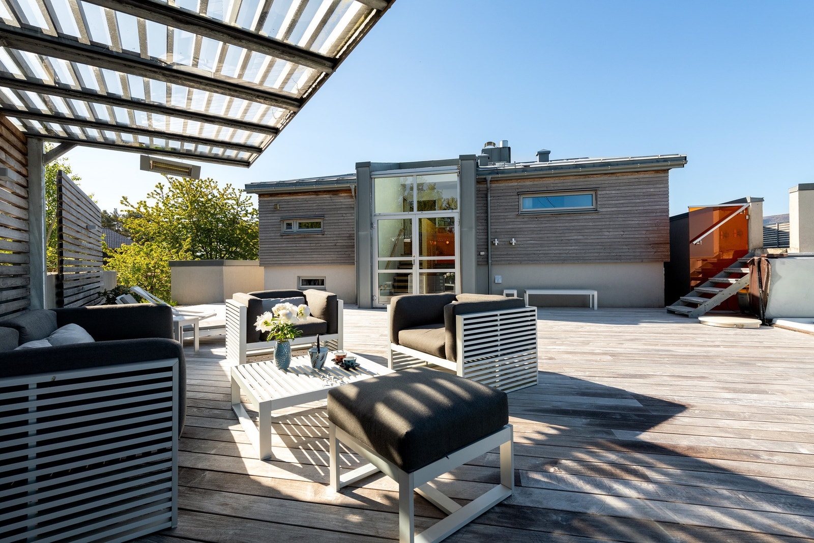 Fasade av huset samt stor hovedterrasse med god plass til flere soner og sittegrupper. Galleribilde