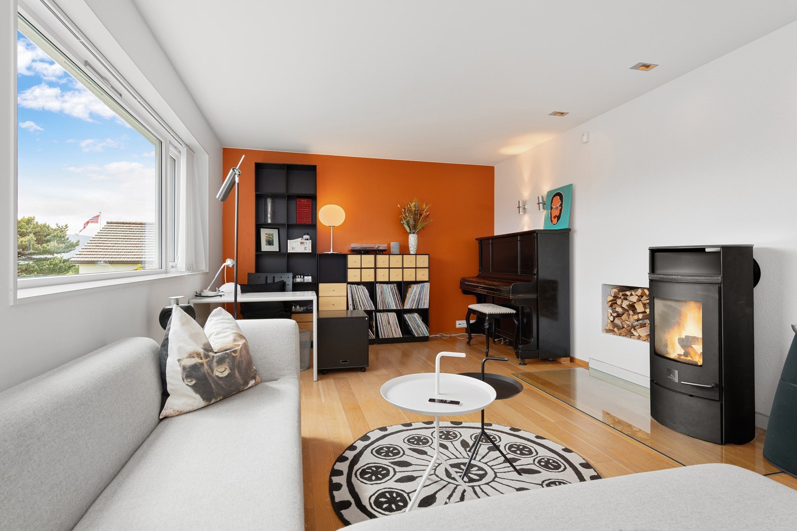 Stue i 1. etasje med en-stavs eikeparkett på gulv, malte vegger og tak. Peisovn med glassdør som gir en lun og hyggelig atmosfære. Galleribilde