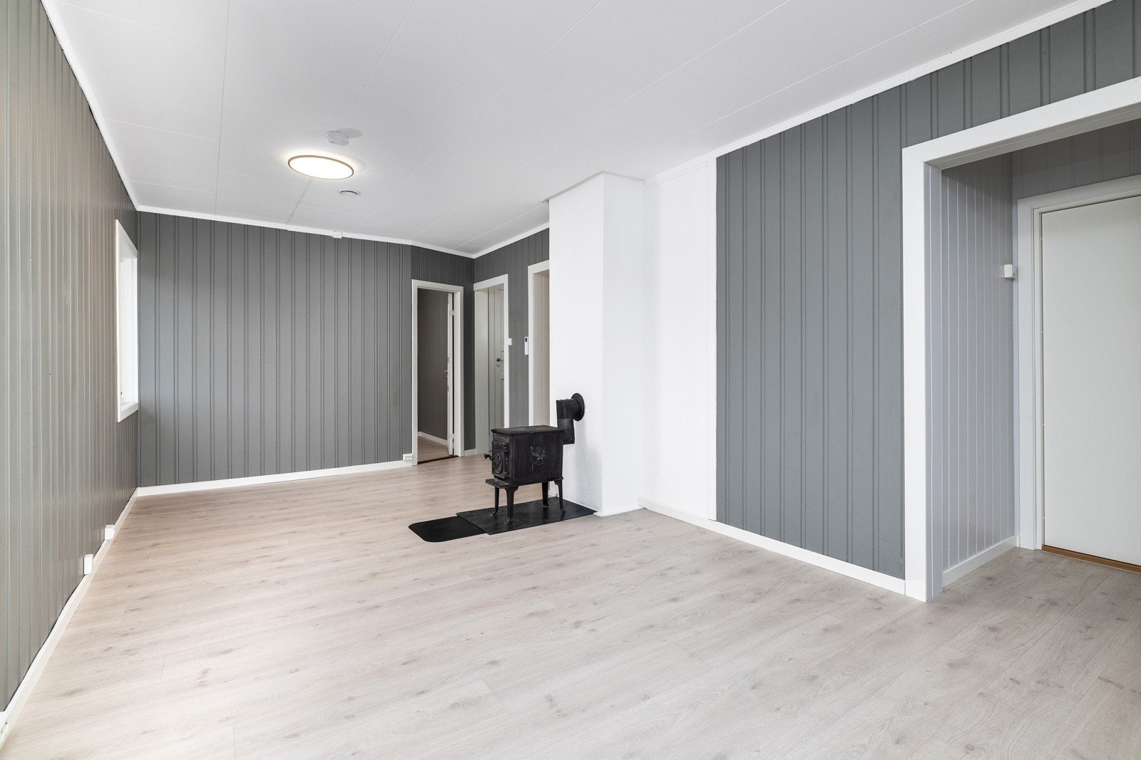 Lys og hyggelig stue med laminatgulv og malte plater på veggene. Galleribilde