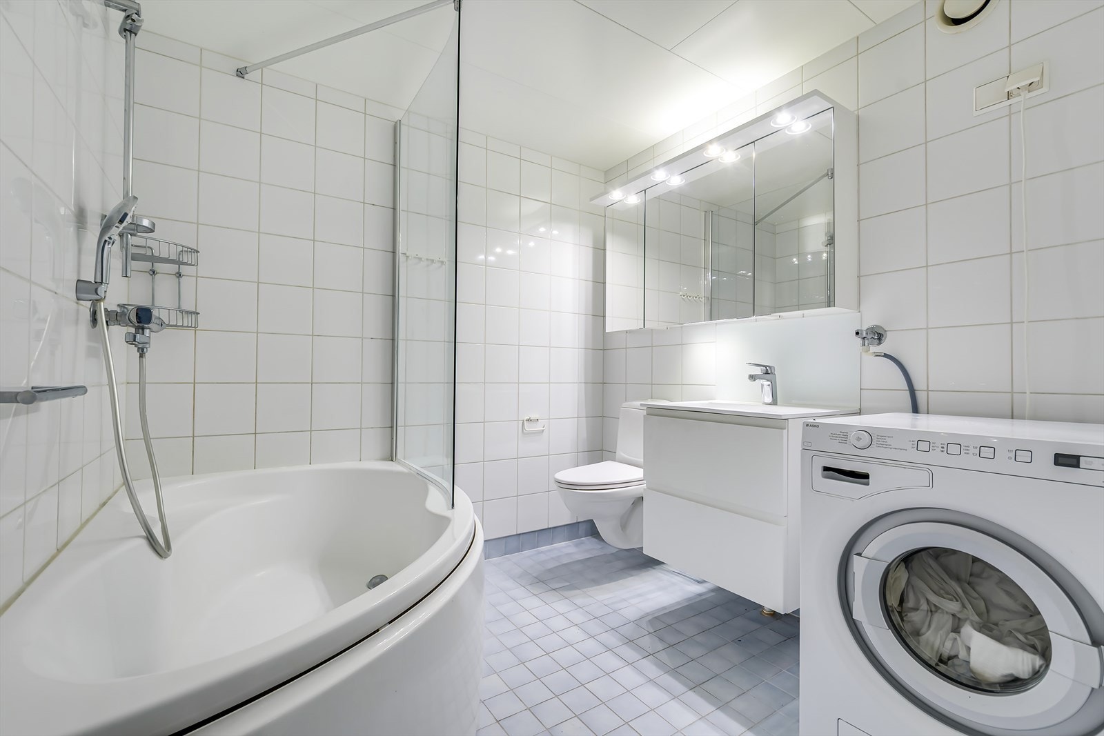 Ifm. mellomgang/entré finner man leilighetens bad. Badet er et modulbad fra byggeår og oppleves romslig og velutnyttet. Varmekabler i baderomsgulvet. Galleribilde