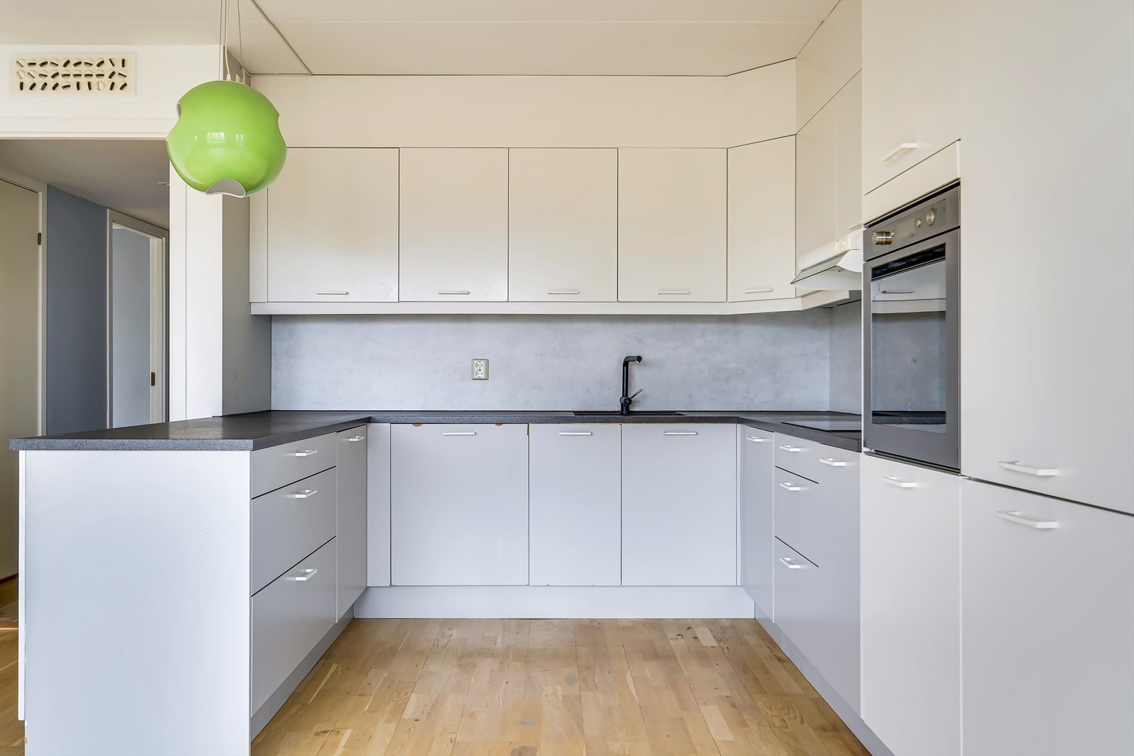 Kjøkkeninnredning med glatte fronter, benkeplate i laminat med kum og ett-greps blandebatteri. Utstyrt med hvitevarer som komfyr, platetopp, oppvaskmaskin, kjøl/ fryseskap samt ventilator over kokesone. Galleribilde