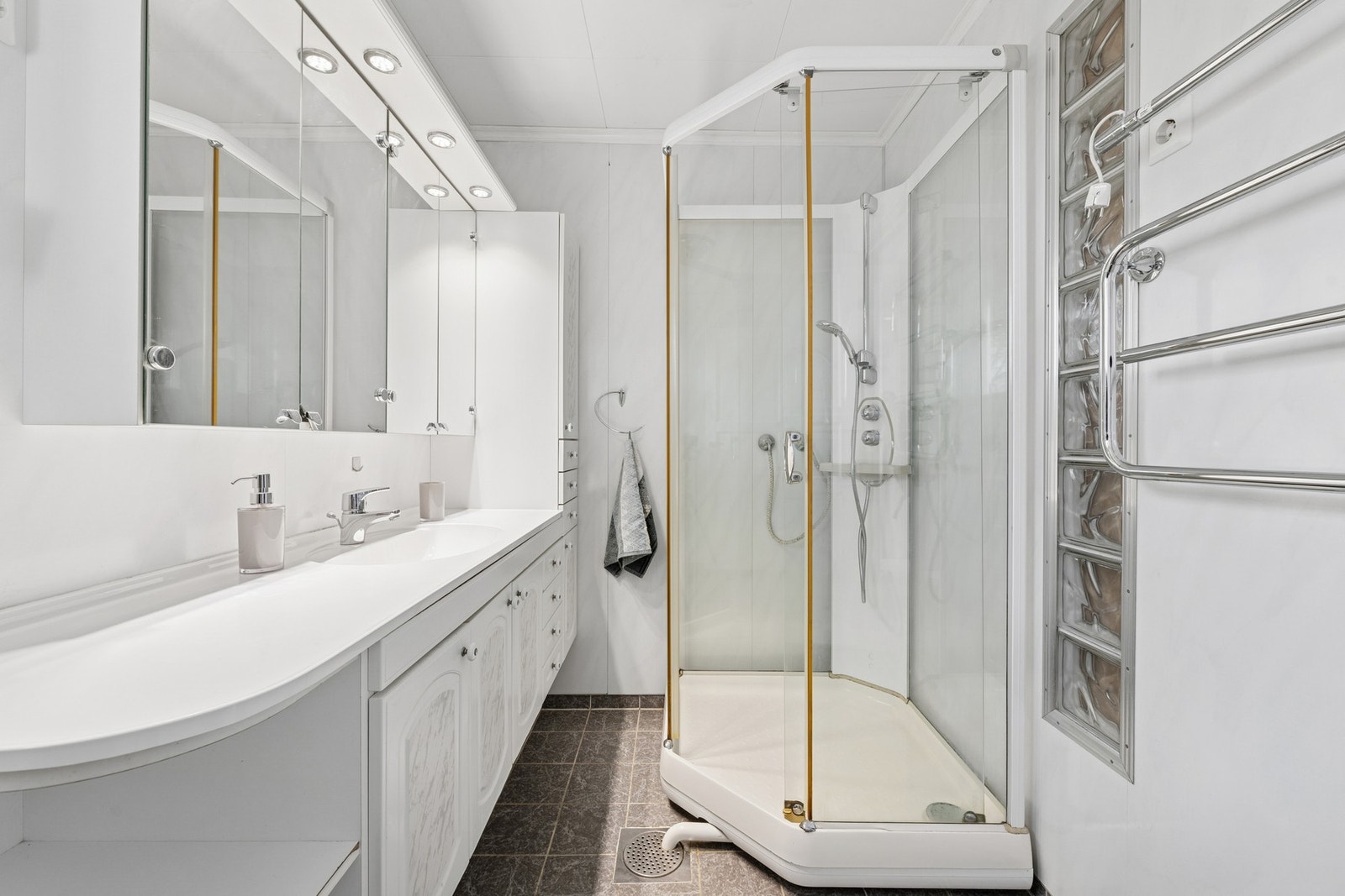 Rommet er innredet med dusjkabinett, servant med innredning og speil. Det er varme i gulvet. Galleribilde