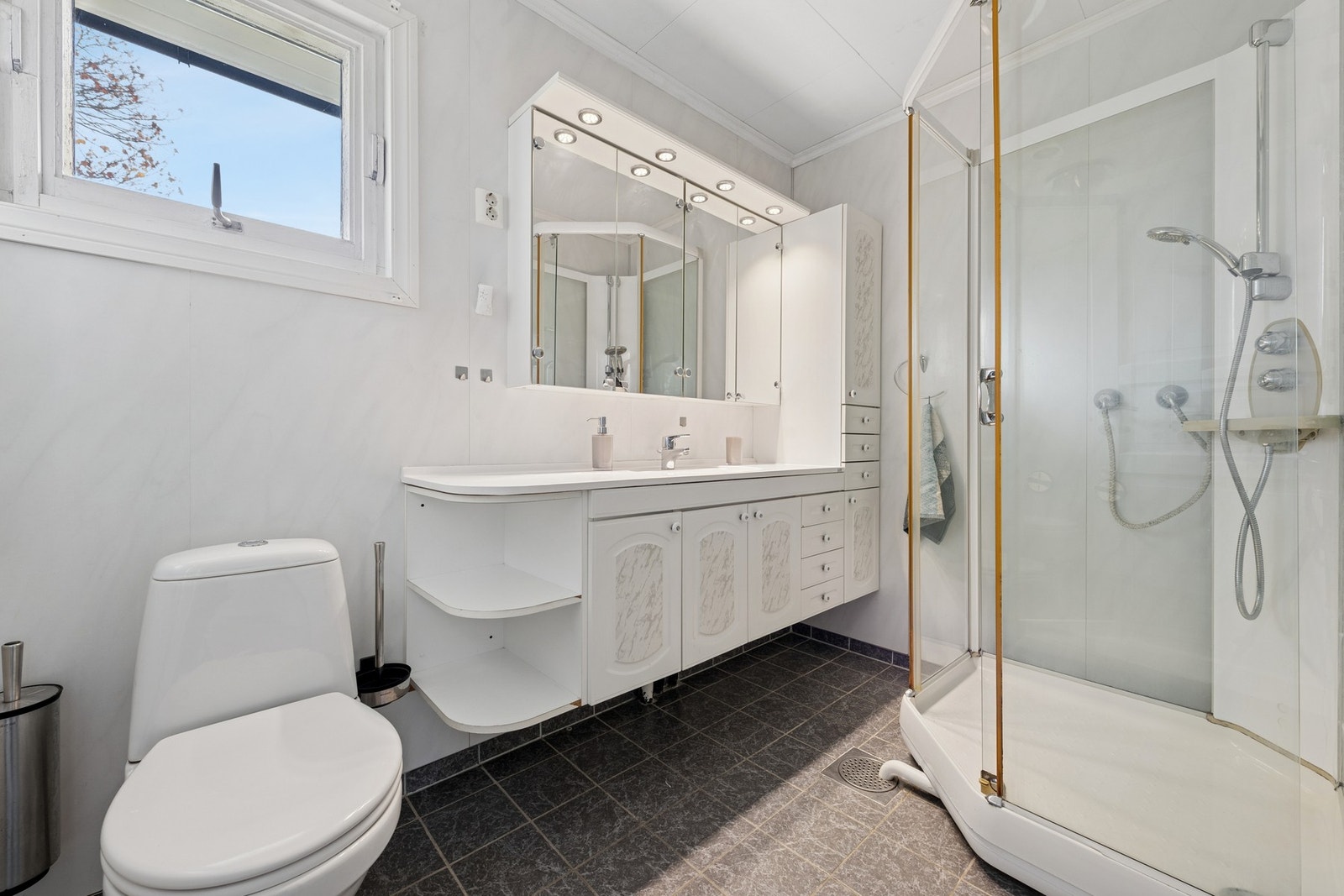 Baderom med flislagt gulv og lyse vegger. Galleribilde