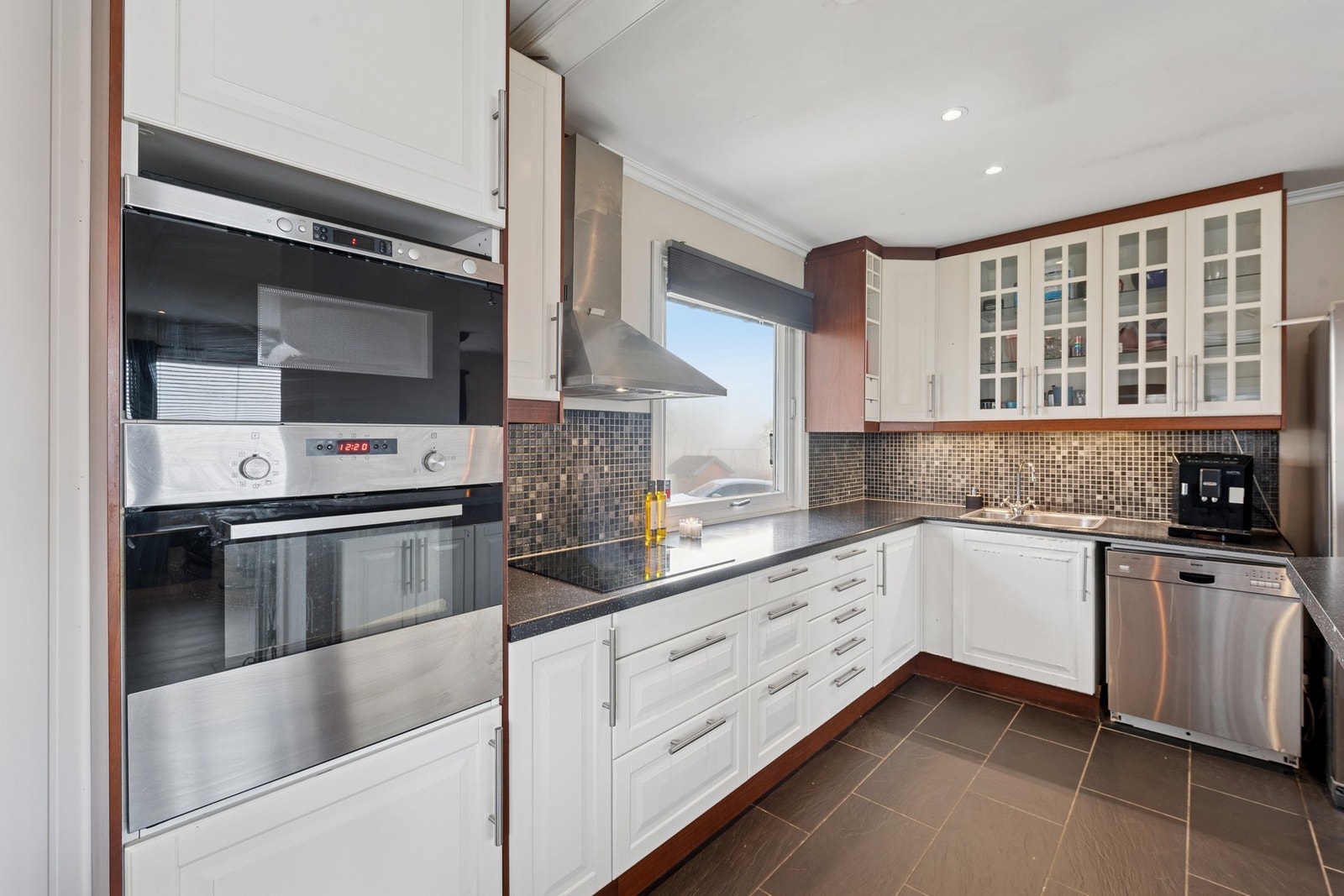 Fliser mellom benk og overskap som gir et tidløst og stilrent uttrykk. Galleribilde