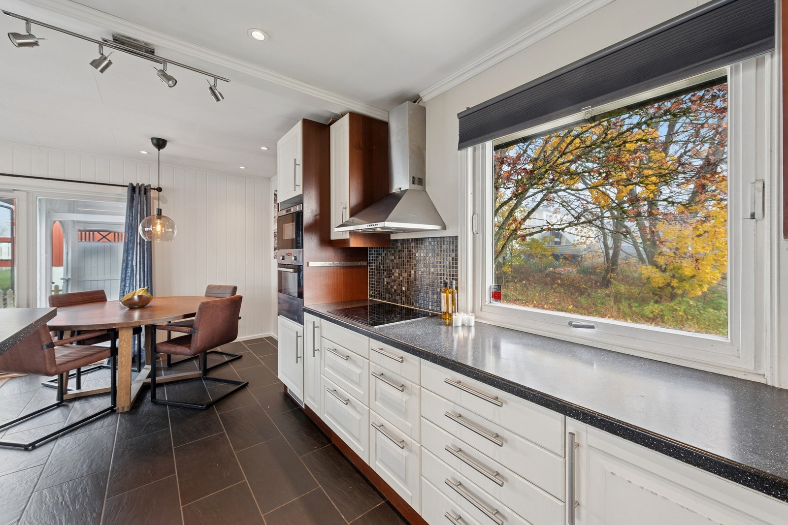 Kjøkkeninnredningen har klassiske, profilerte fronter i hvitt, kombinert med mørke benkeplater i laminat. Galleribilde