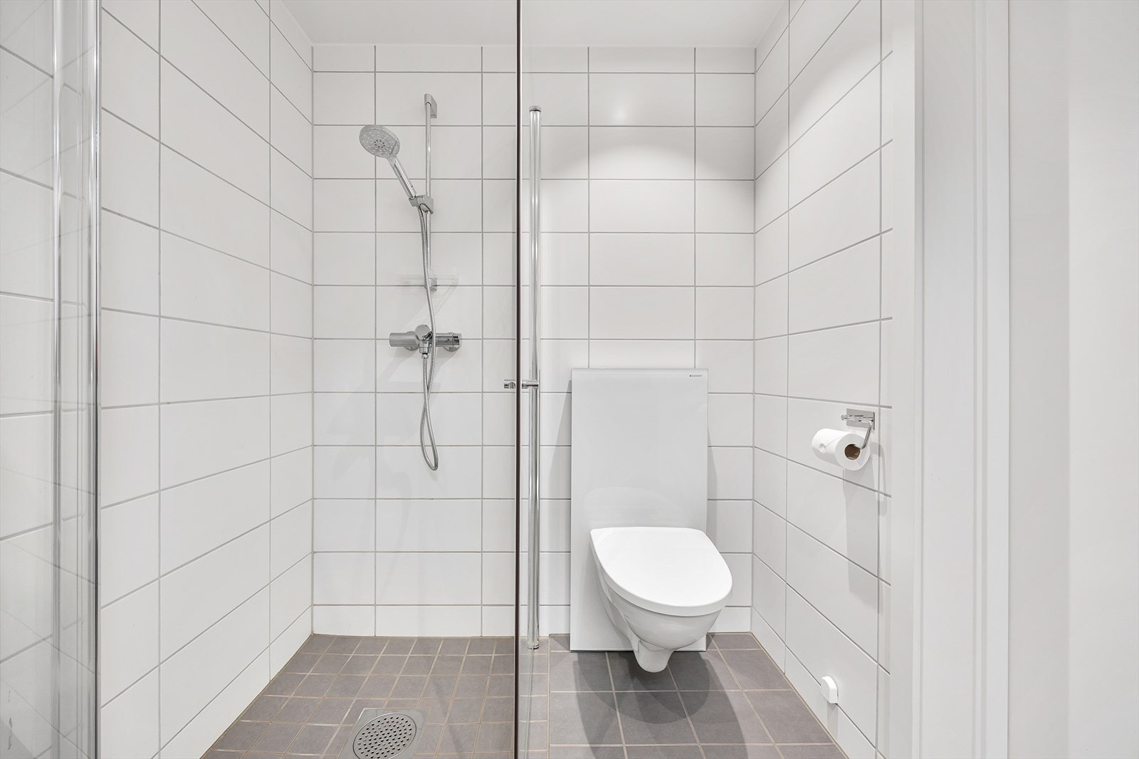 Badet har innredning med nedfelt servant, vegghengt toalett, innfellbare dusjdører og opplegg for vaskemaskin. Galleribilde