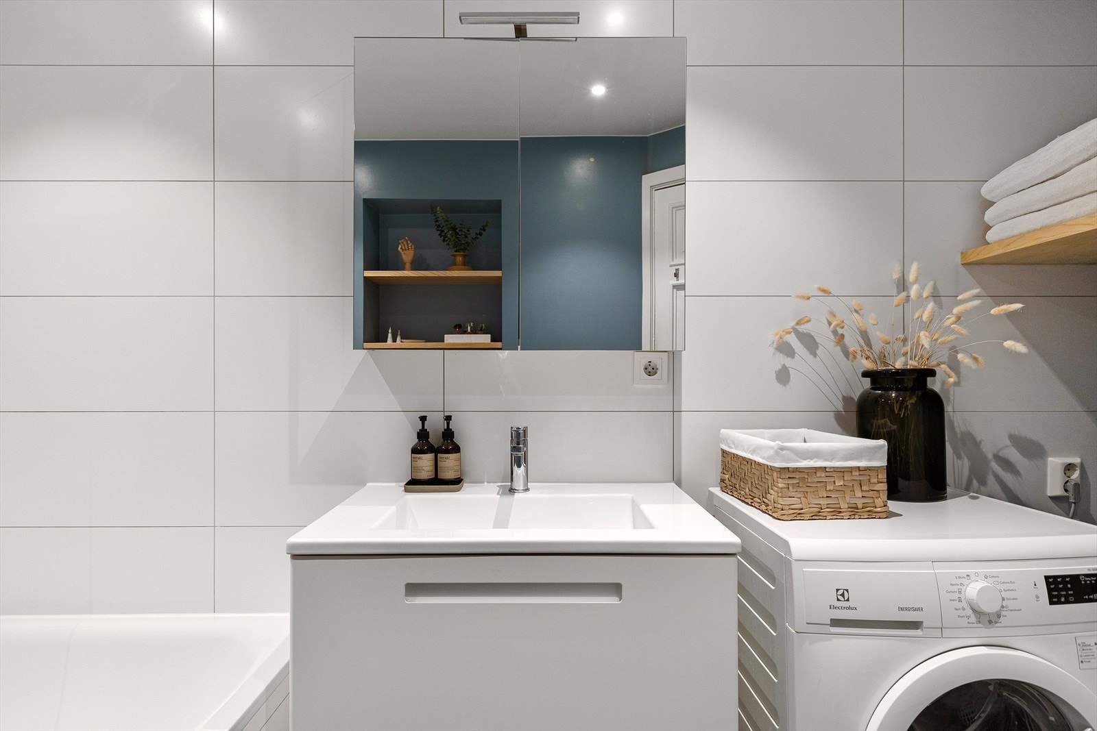 Badet er utstyrt med badekar, veggmontert toalett og baderomsinnredning med en bredde på 80cm med glatt skuff, overlimt servant med ettgreps og speilskap med lys. Galleribilde