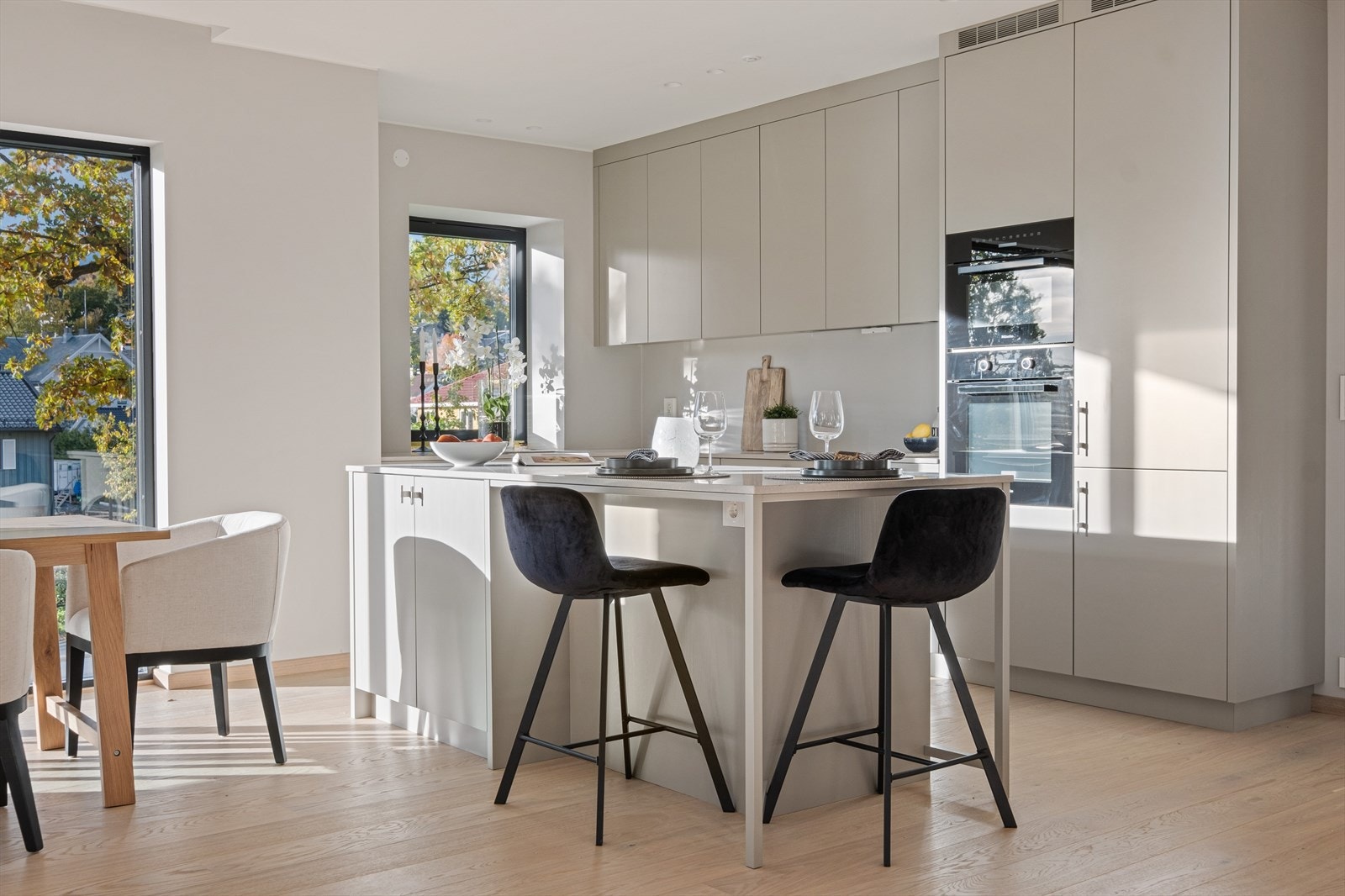 Kjøkkenet inkluderer en praktisk kjøkkenøy og har granittfarget kompositt benkeplate. Frontene er i en moderne, diskret stil, og hele innredningen holder en høy håndverksmessig kvalitet. Bildet er fra leiligheten i 1. etasje. Galleribilde